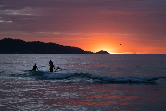 A couple of people riding a wave on top of a surfboard