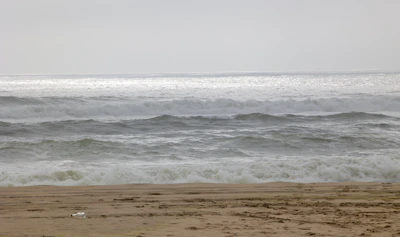 A person walking on the beach with a surfboard
