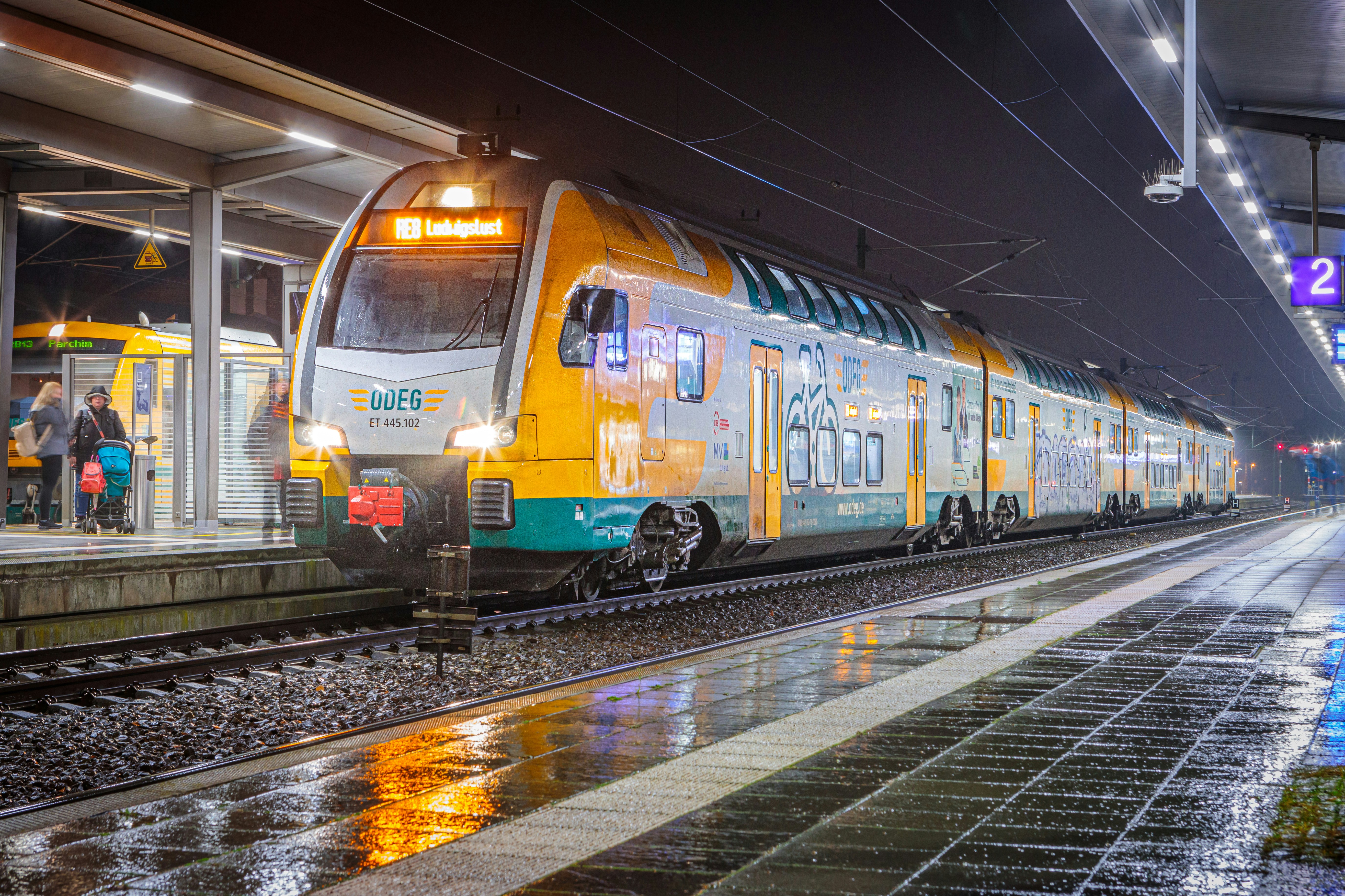 A yellow and green train pulling into a train station