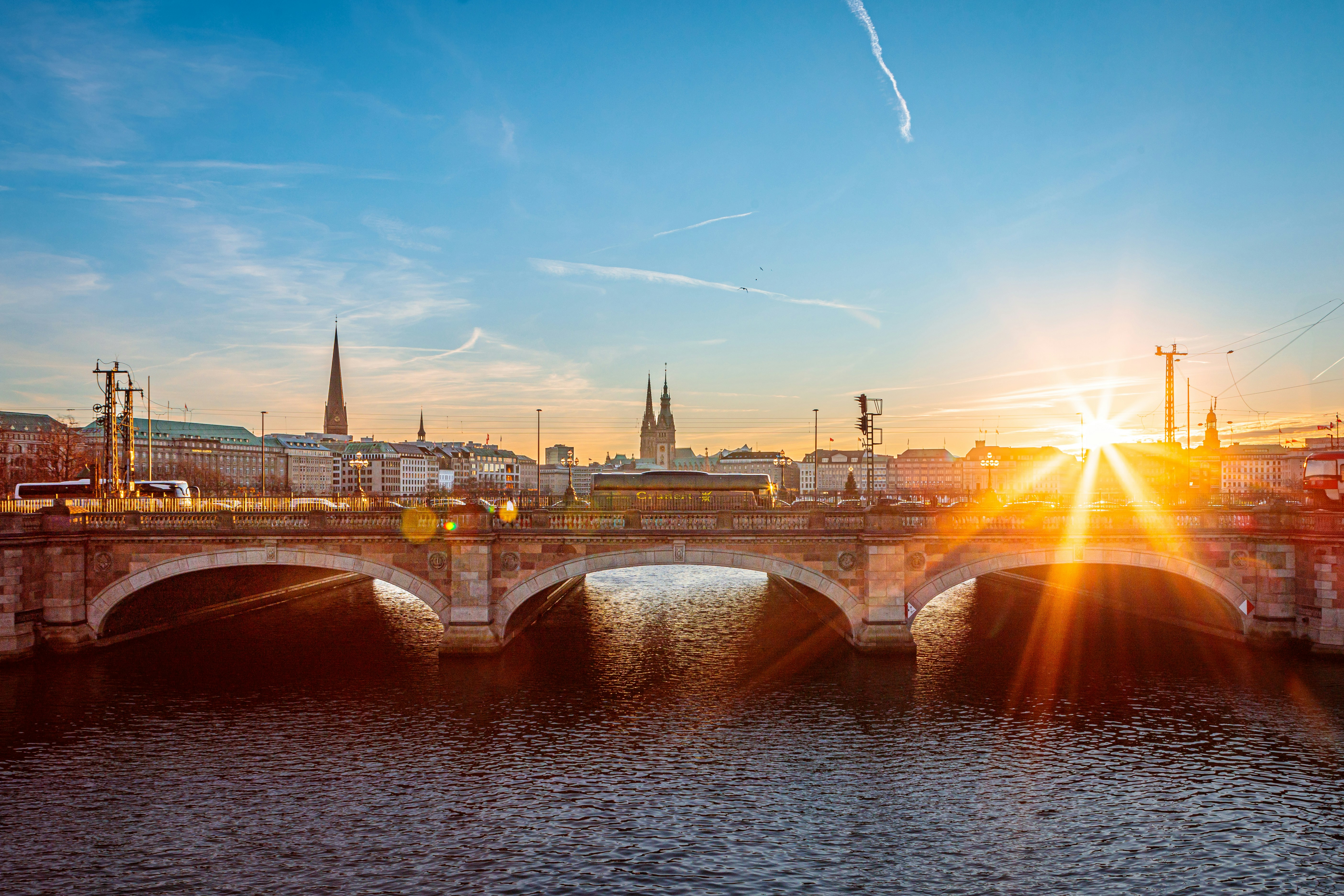 The sun is setting over a bridge over a river