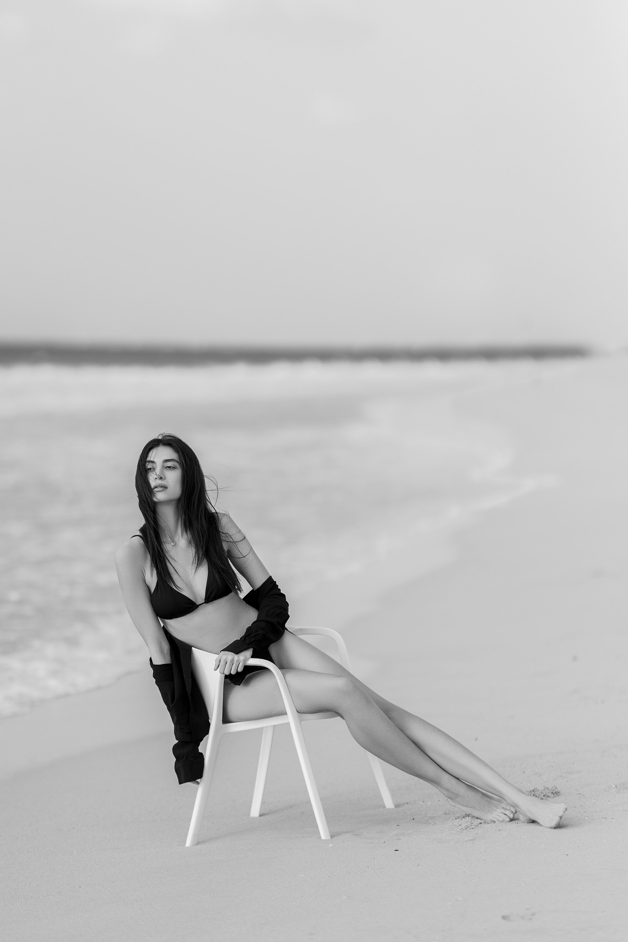 A woman is sitting on a chair on the beach