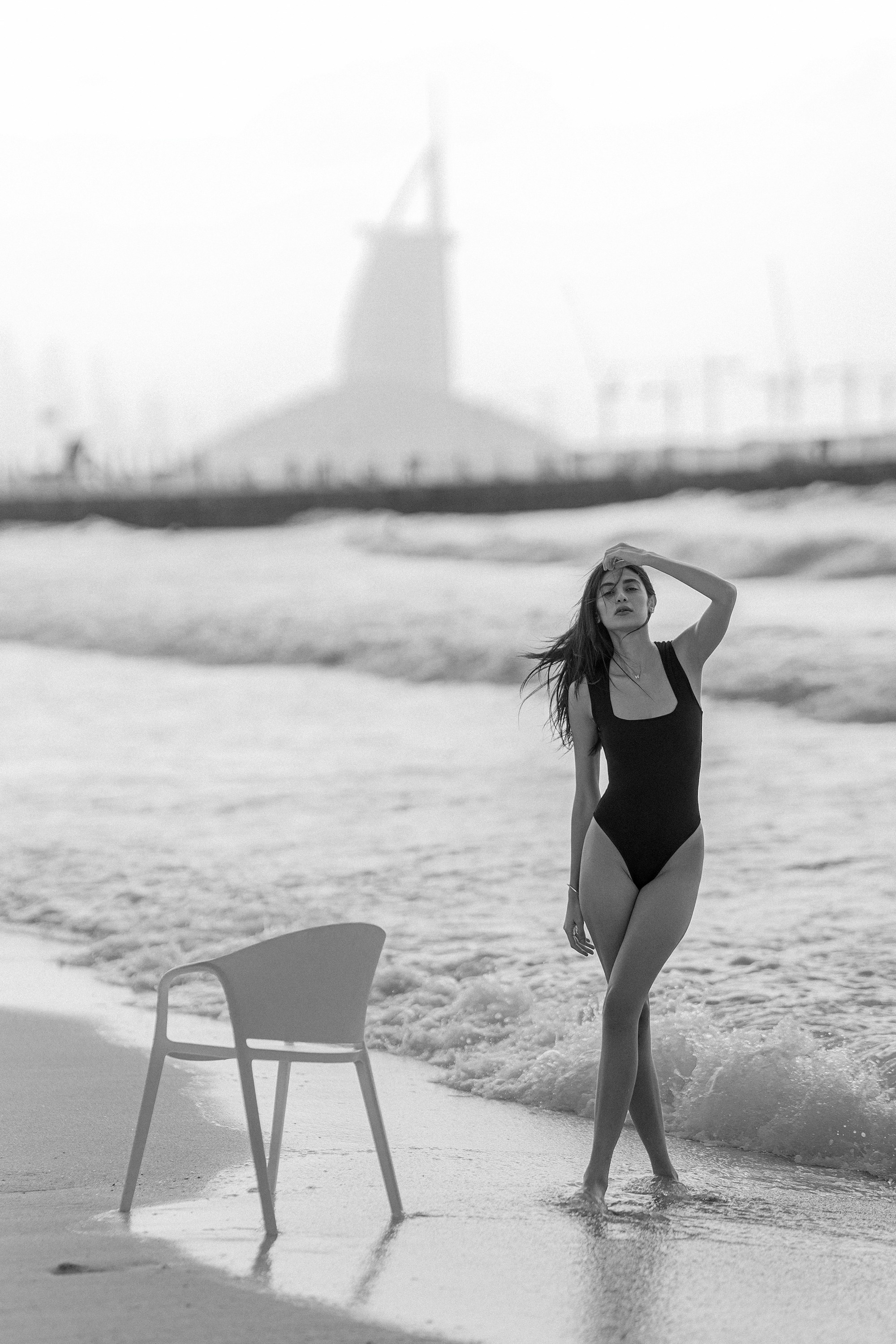 A woman standing on a beach next to a chair