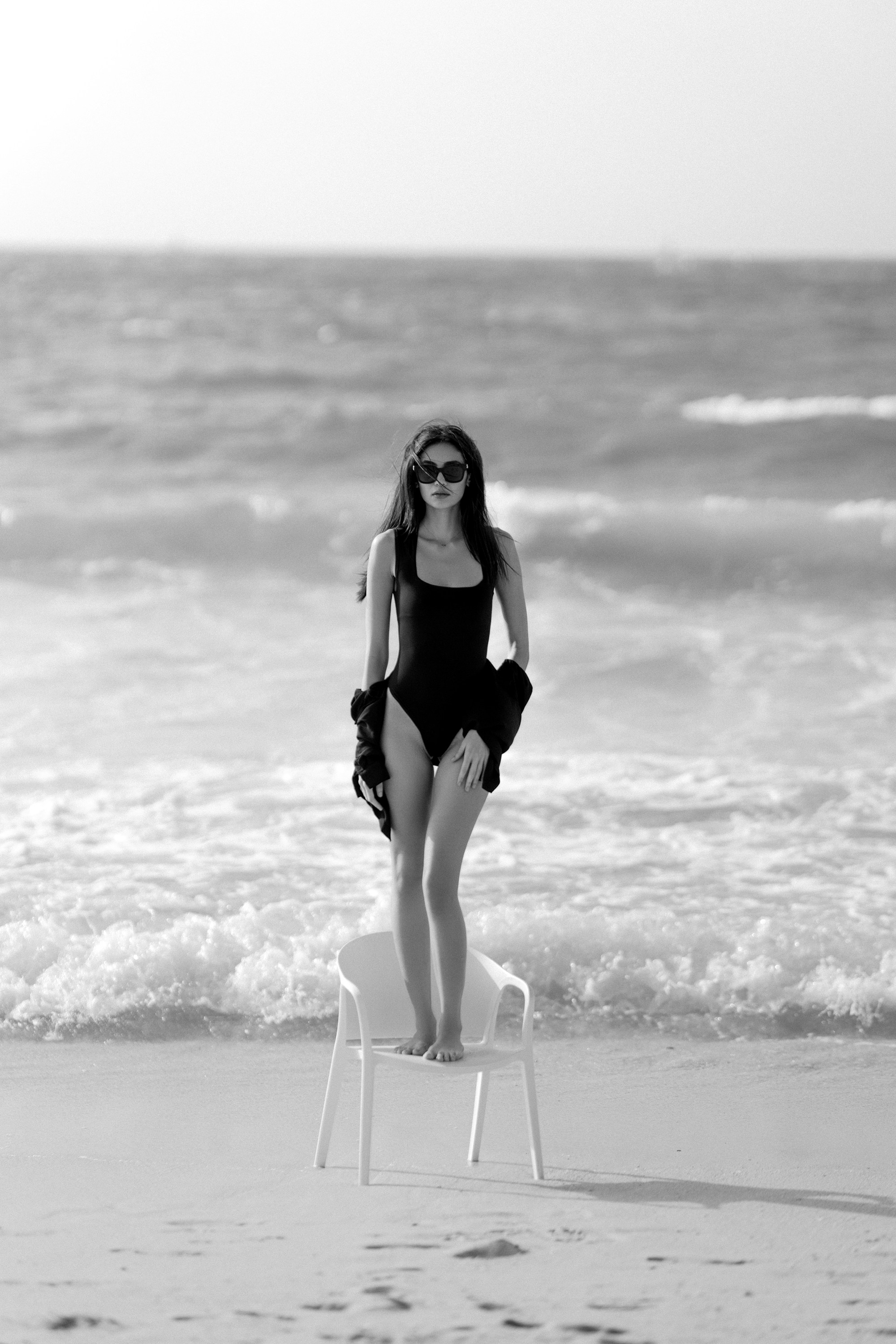 A woman in a bathing suit sitting on a chair on the beach
