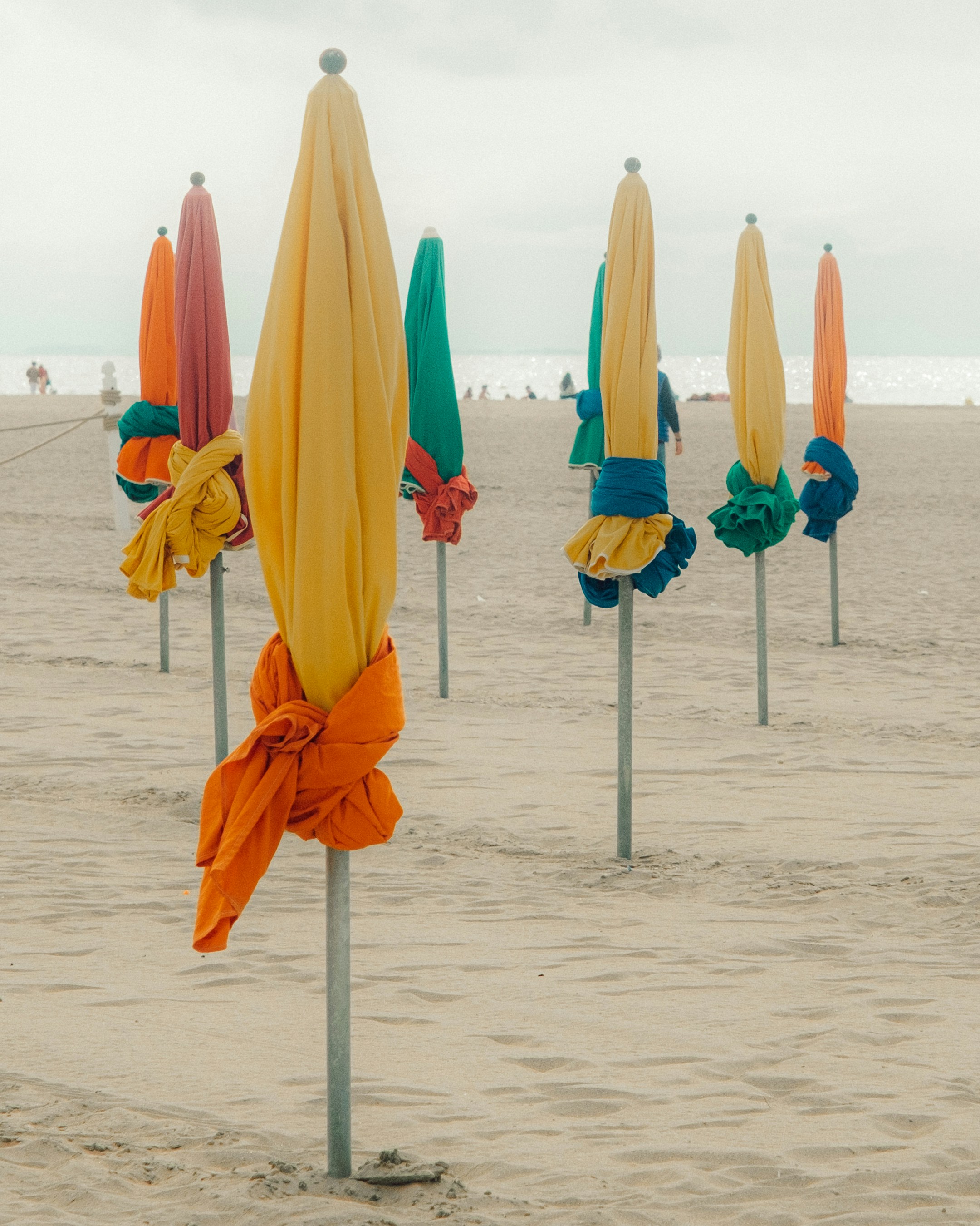 A bunch of umbrellas that are in the sand