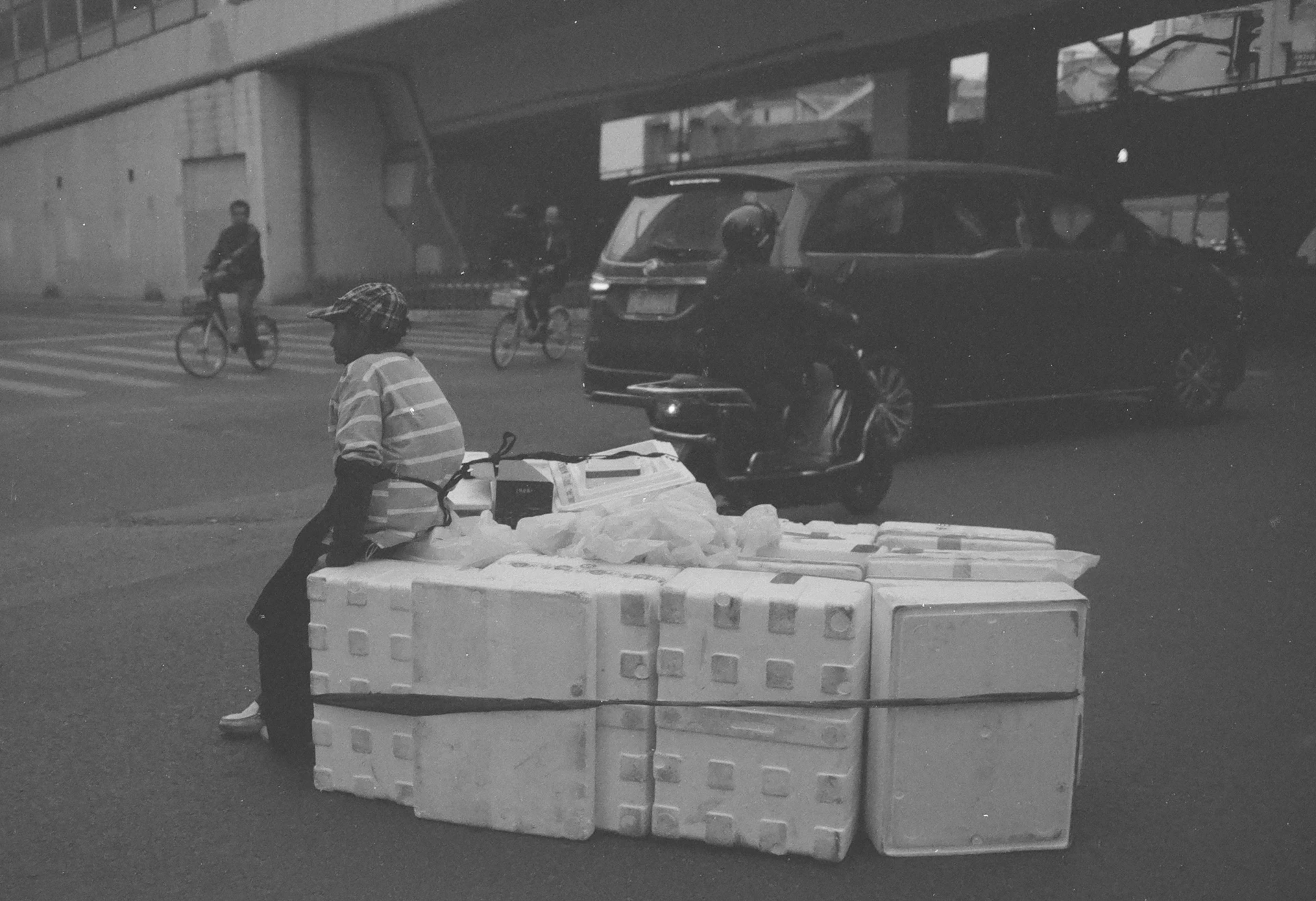 A black and white photo of a person sitting on a box