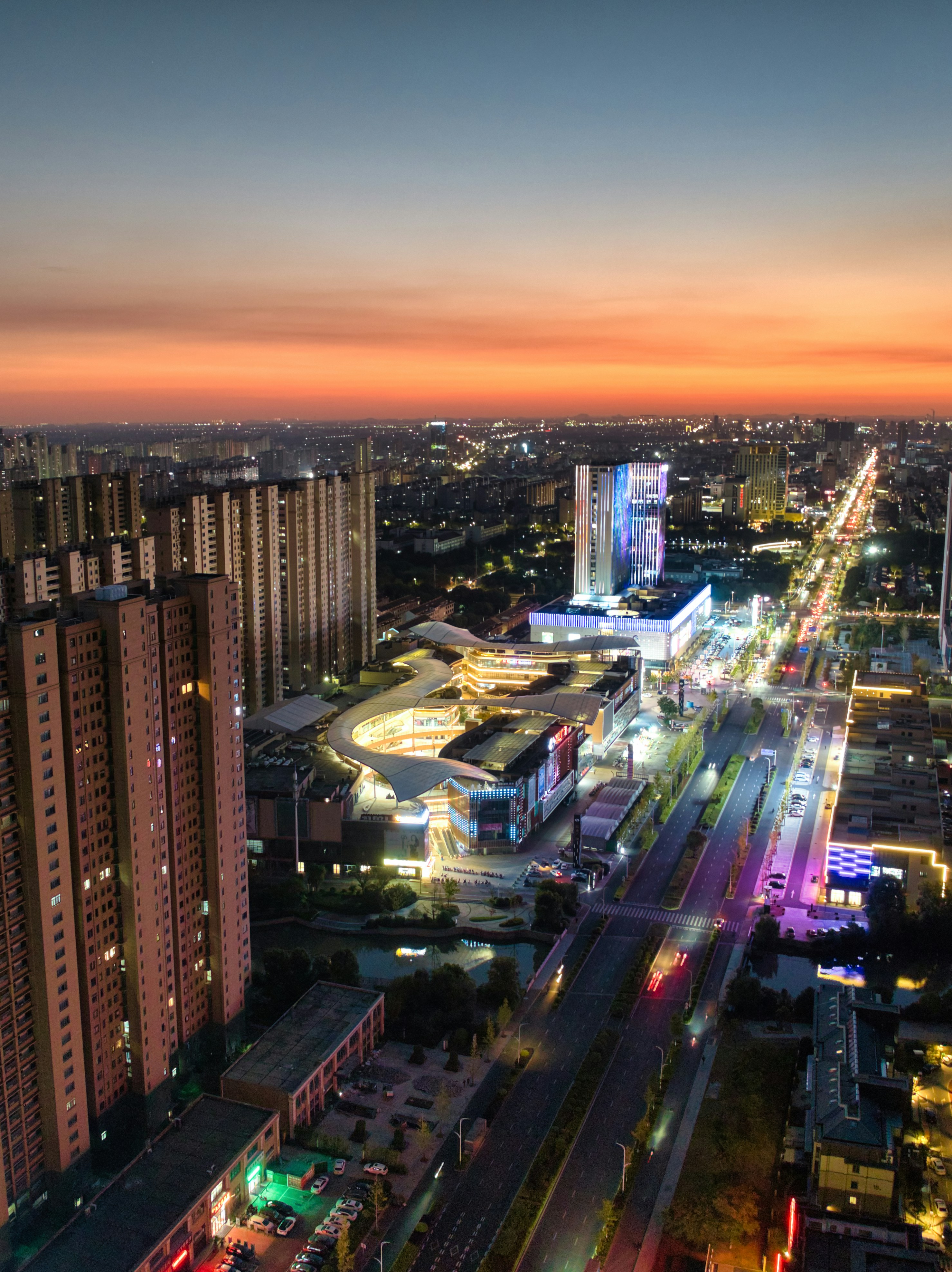 City buildings and a busy highway glow at dusk.