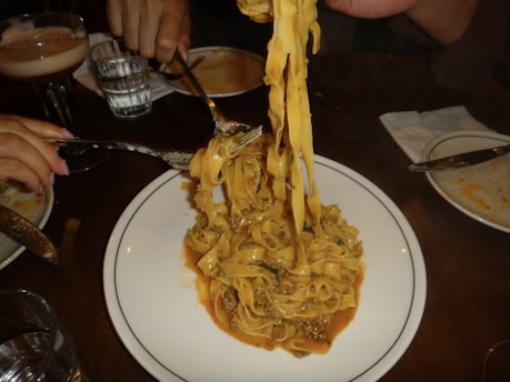 A plate of pasta being lifted with a fork