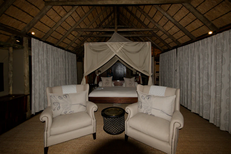A luxury safari suite interior with a canopy four-poster bed under a thatched roof