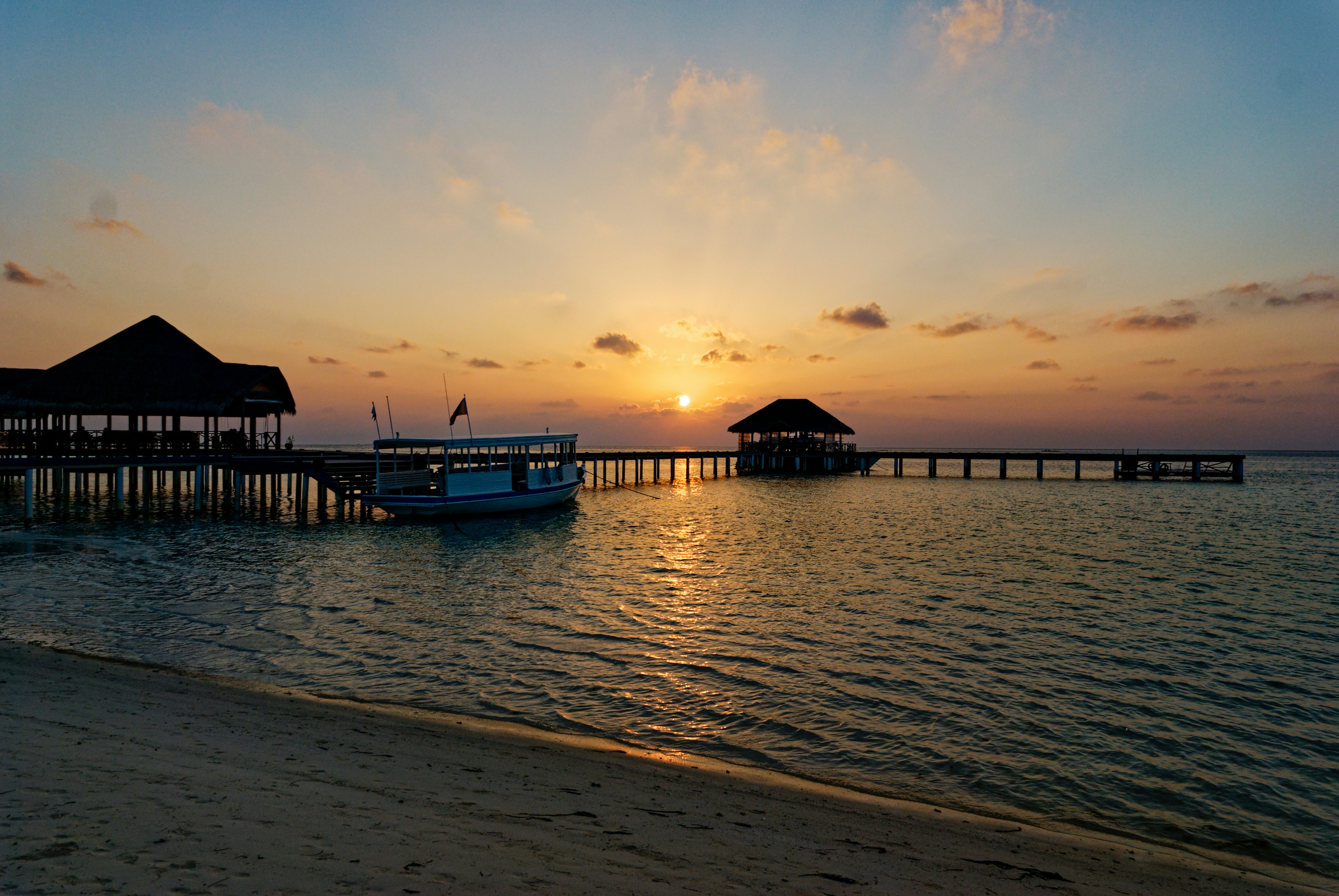 The sun is setting over the water at the beach
