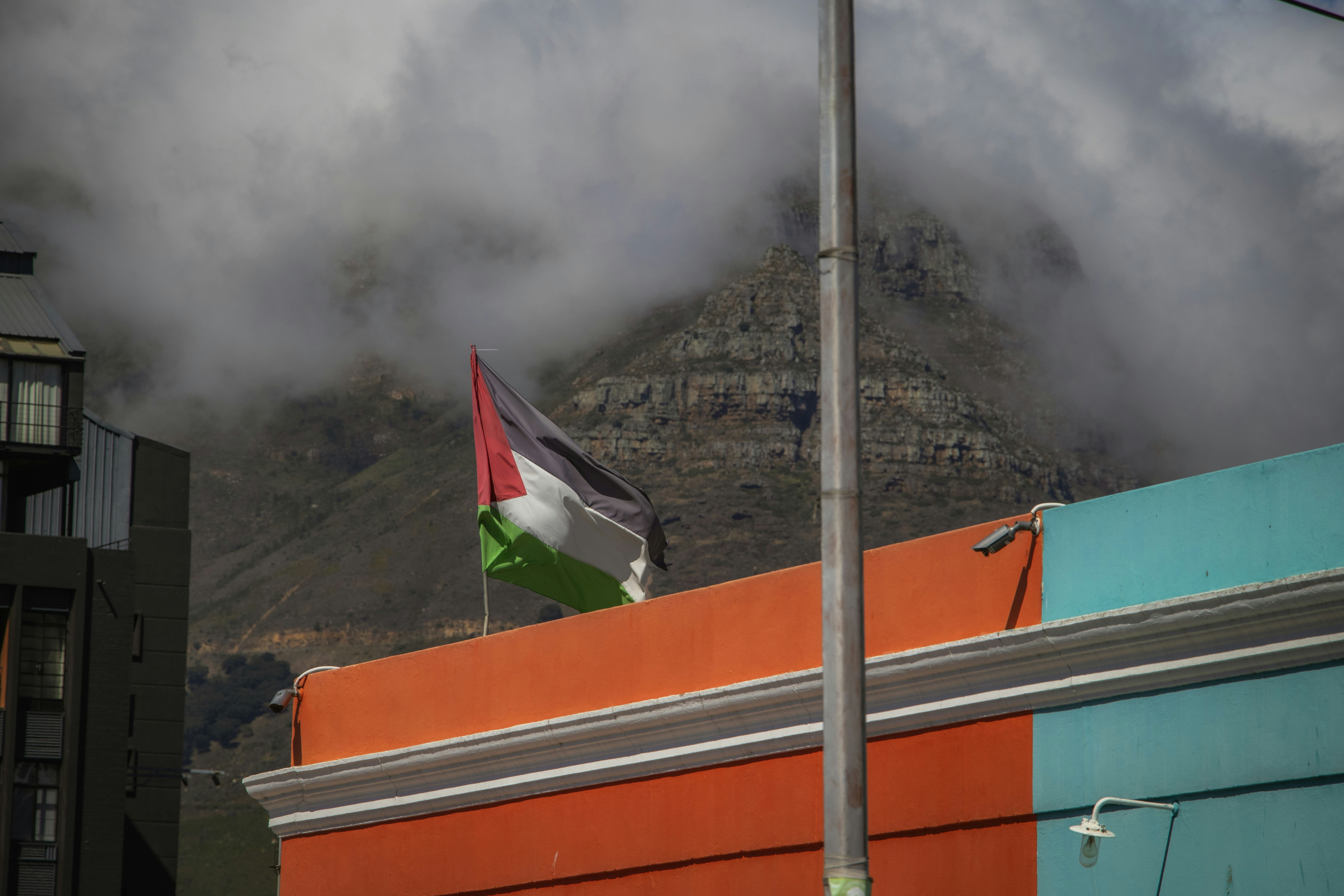 A flag flying in the wind with a mountain in the background