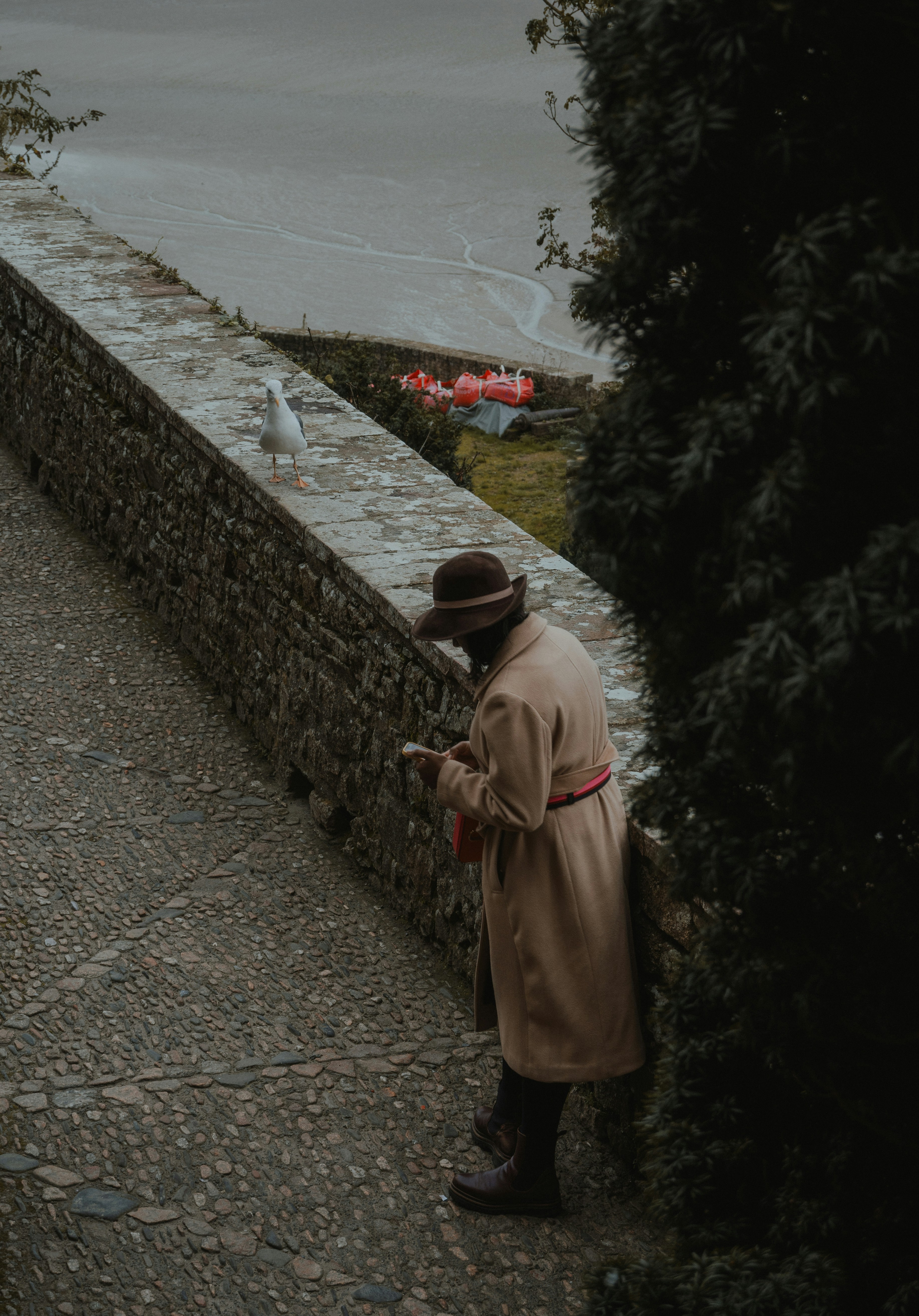 Un uomo in un trench che guarda il suo cellulare