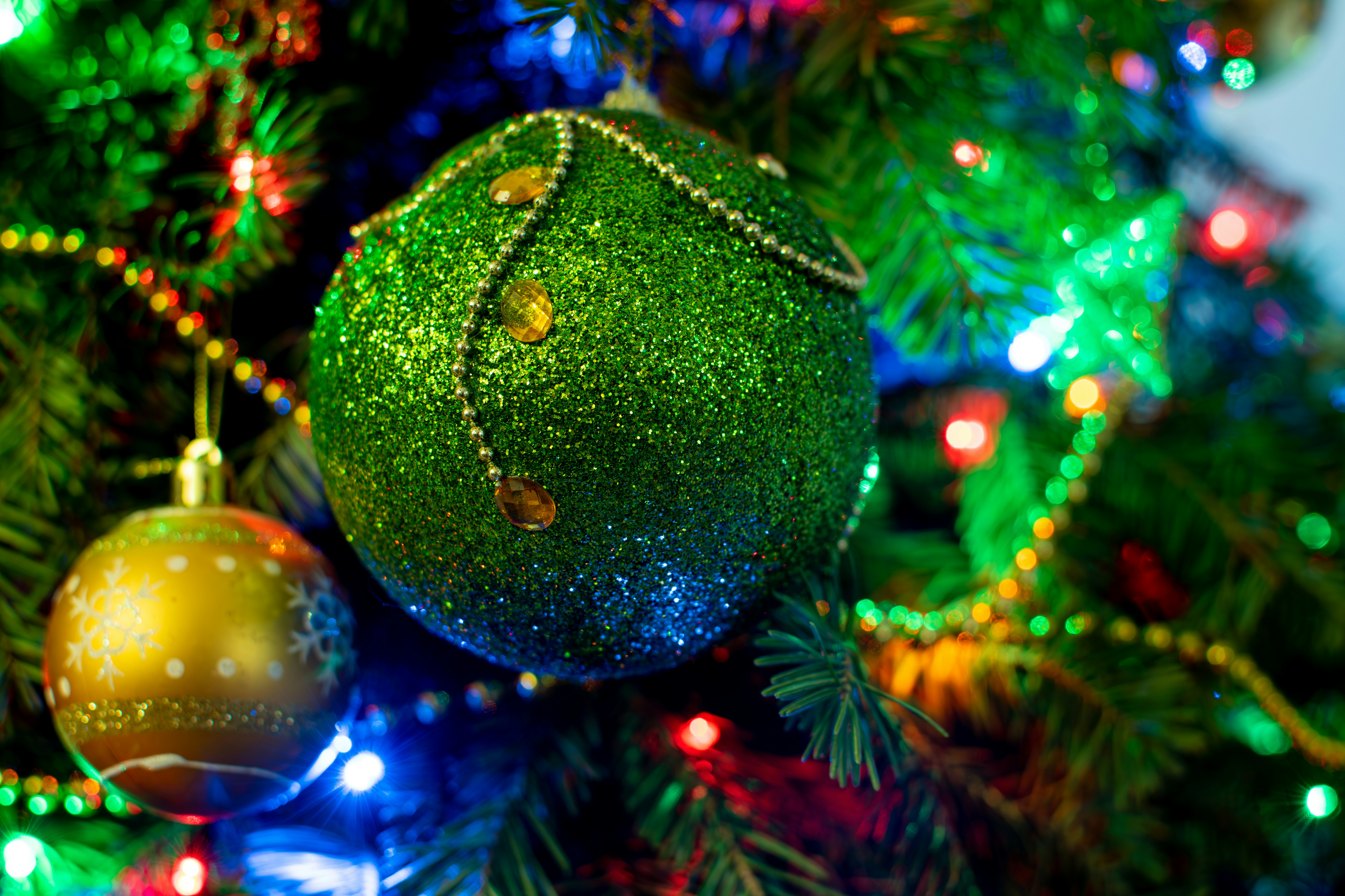 a green christmas ornament hanging from a christmas tree