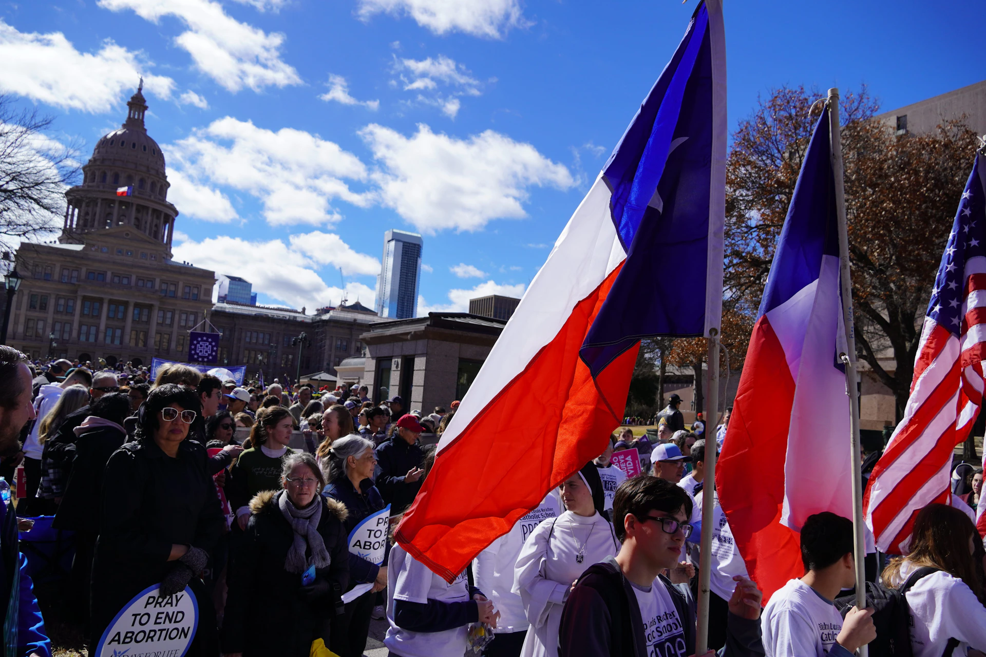 A group of people walking down a street holding flags
