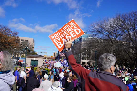 A man holding up a red sign in front of a crowd of people