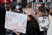 A group of people holding signs in front of a building