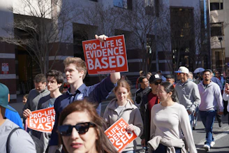 A group of people walking down a street holding signs