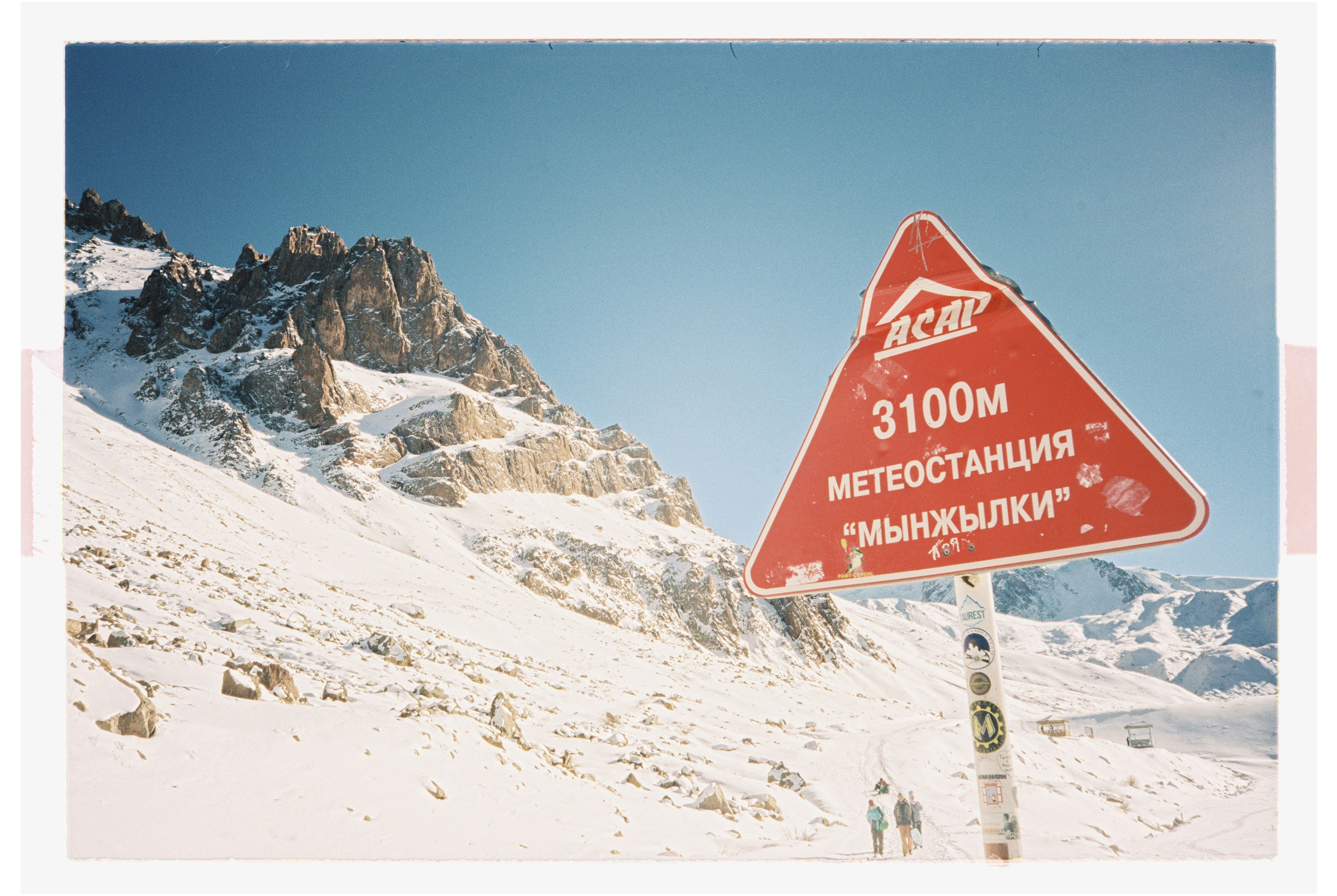 A red street sign sitting on the side of a snow covered mountain