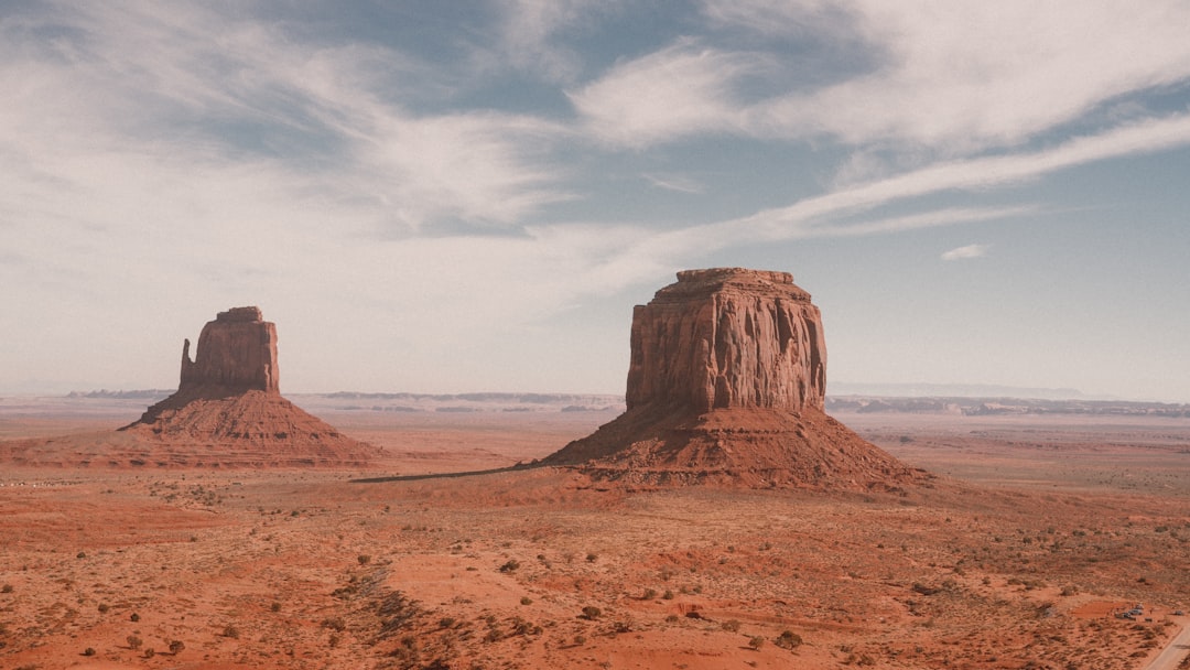 A desert landscape with two large rocks in the distance, Monument Valley