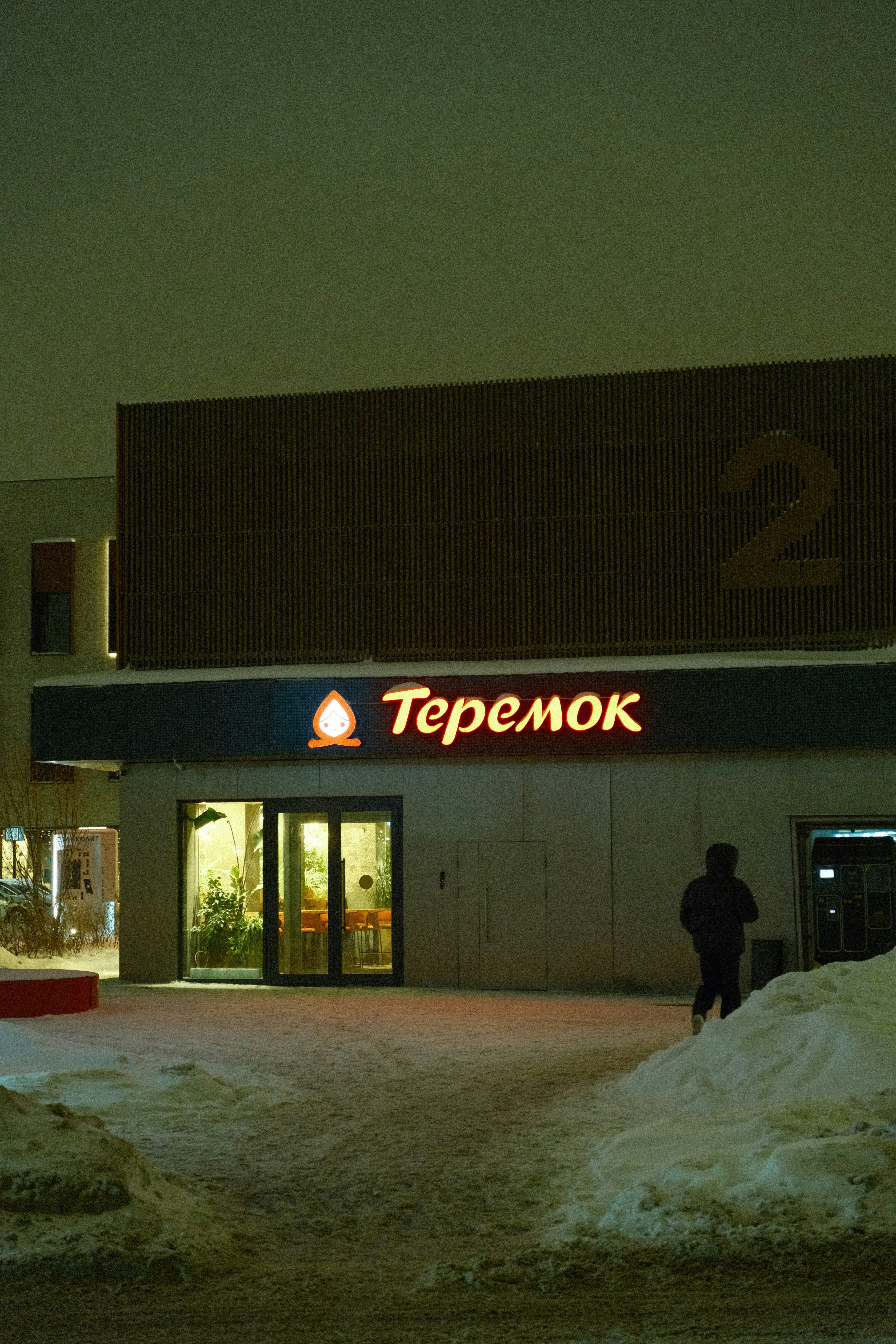 A person standing in front of a store at night