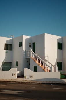 A white building with green shutters and a staircase
