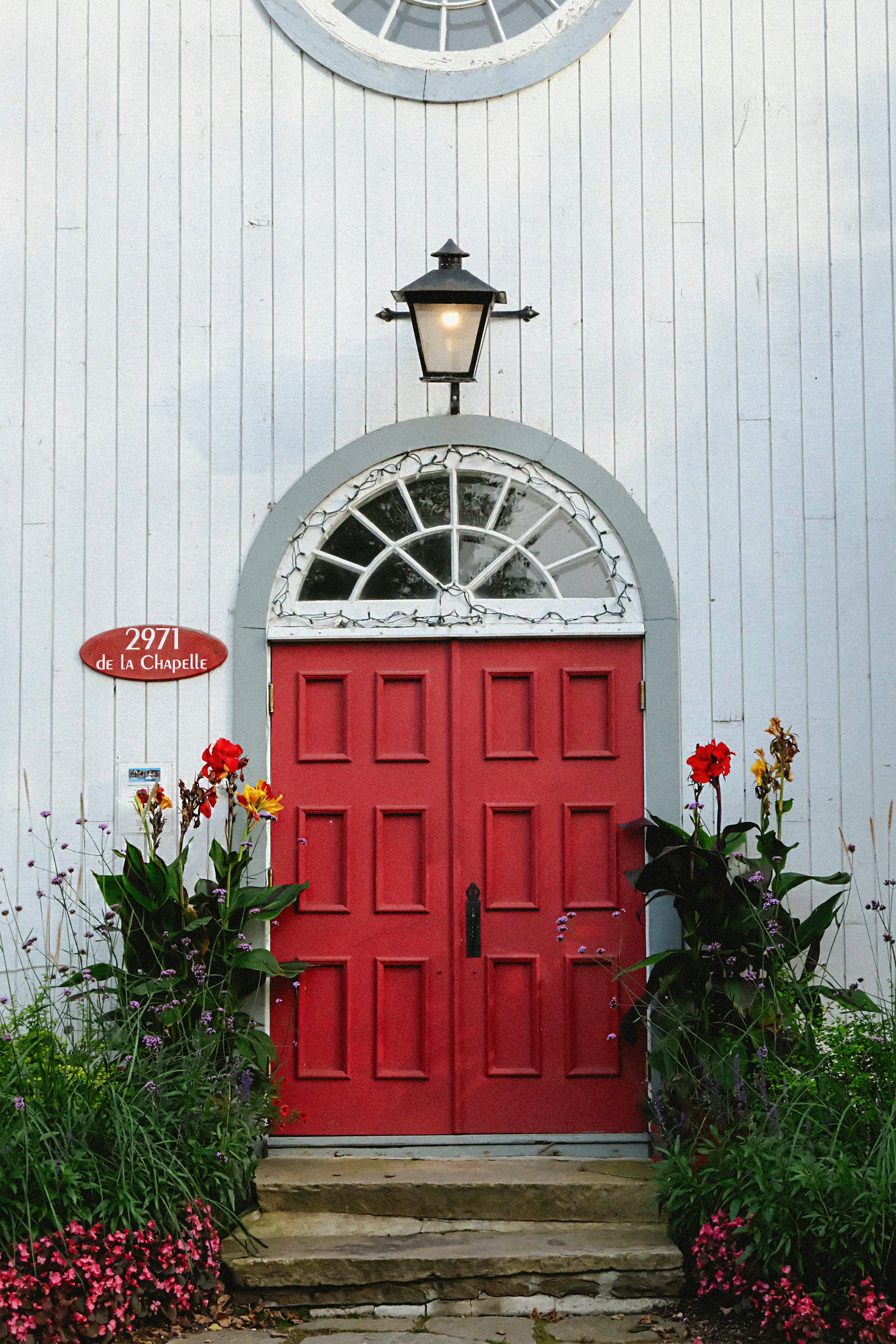 A red door is in front of a white building