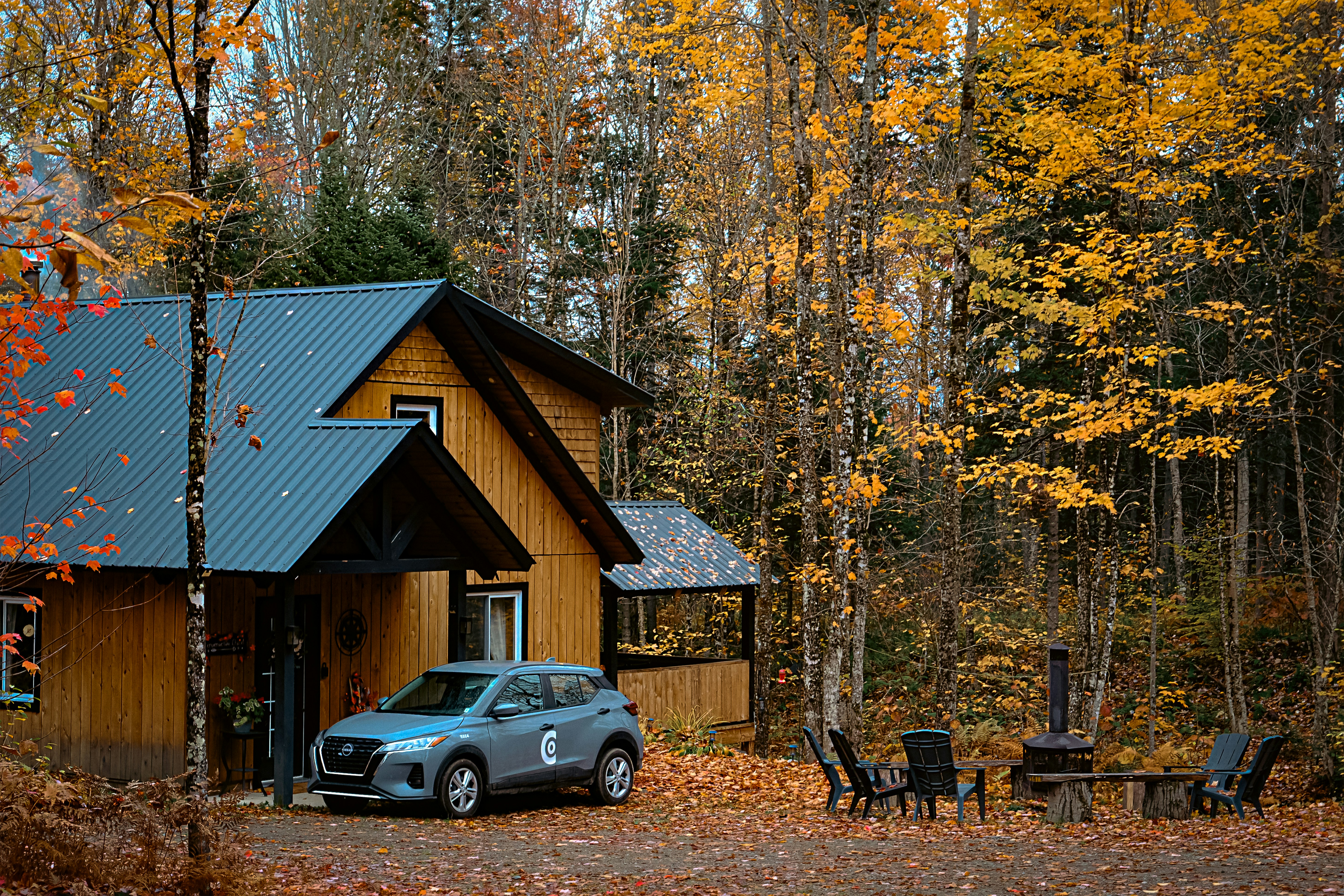 A car parked in front of a cabin in the woods