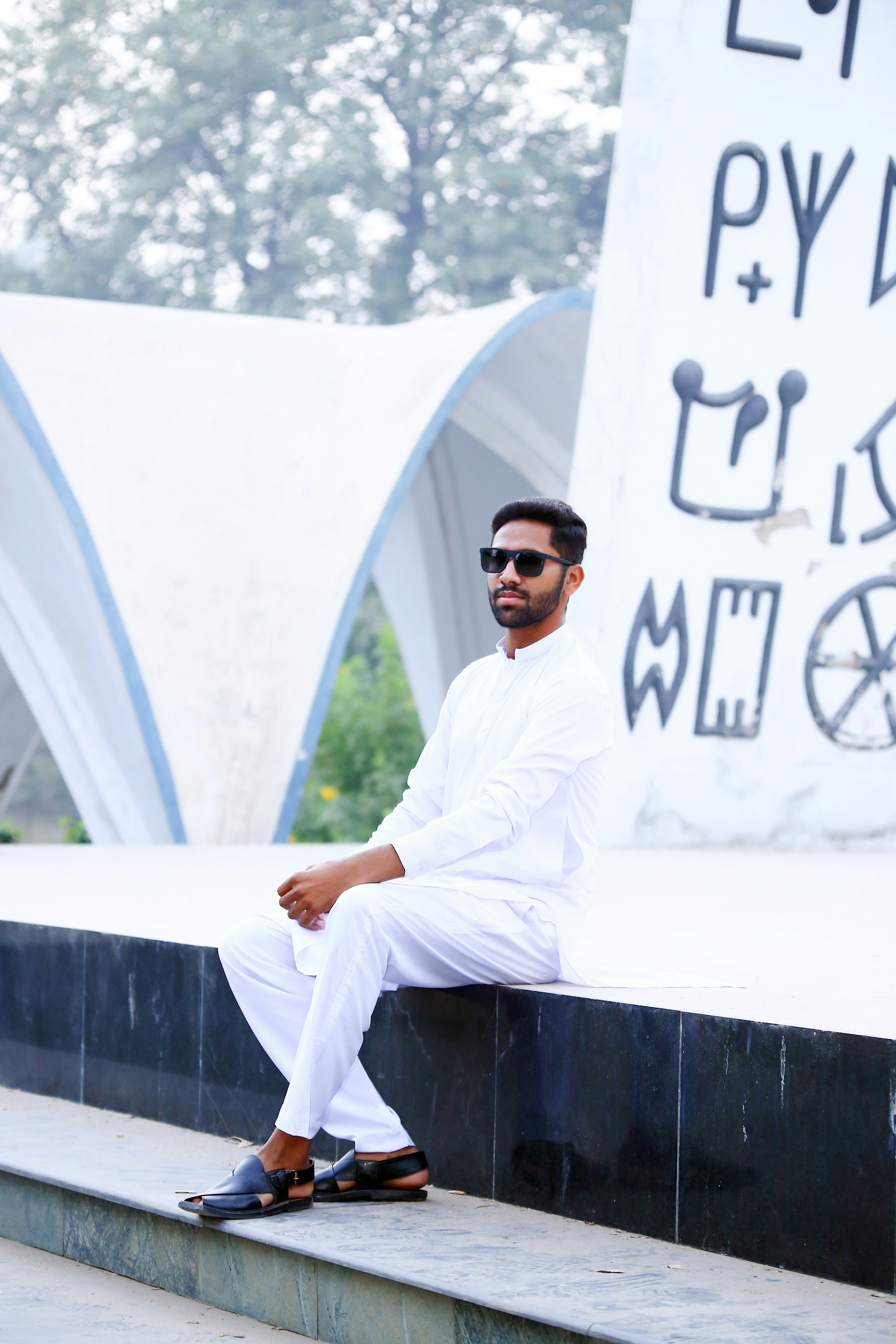 A man sitting on a ledge in front of a building
