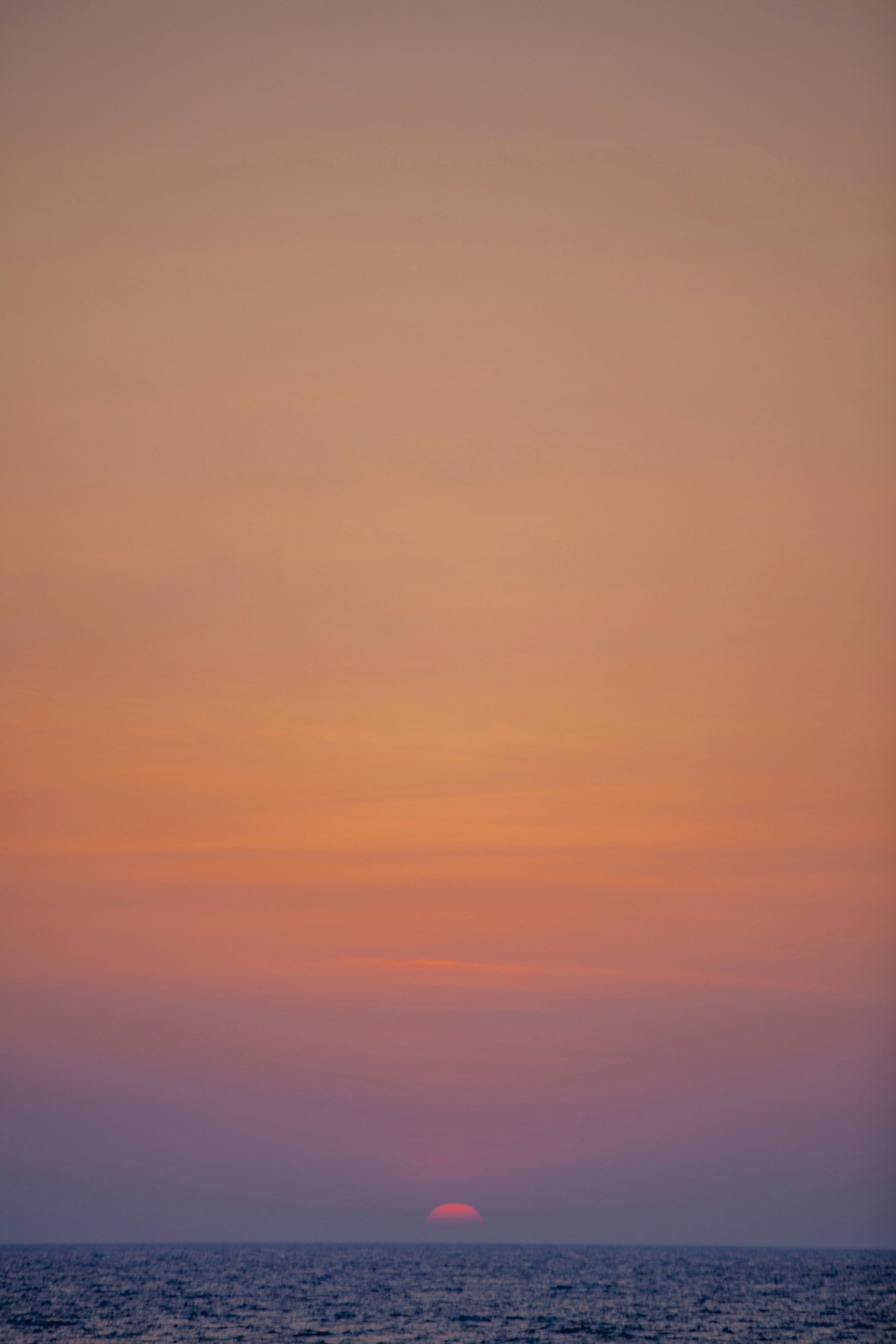 The sun is setting over the ocean on a clear day