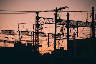 Silhouette of power grid lines against a sunset sky