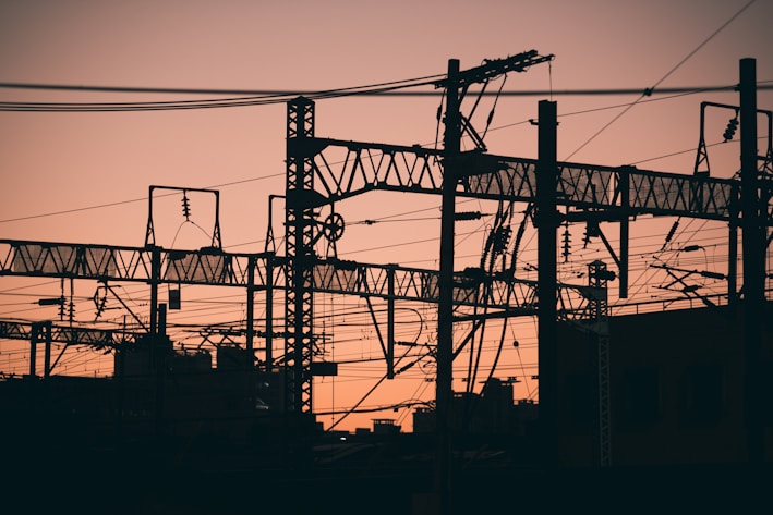 Silhouette of power grid lines against a sunset sky