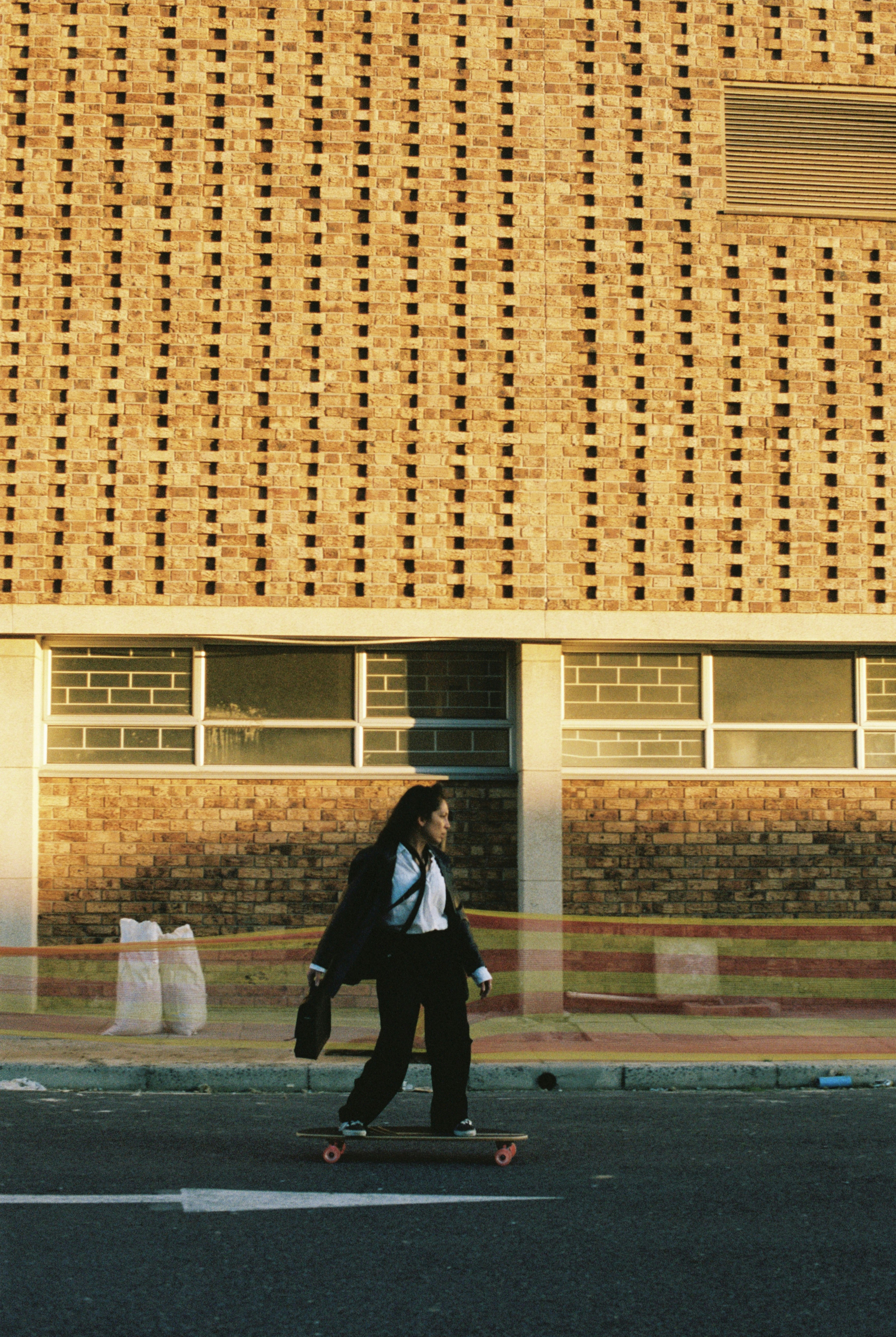 A man riding a skateboard down a street next to a tall building