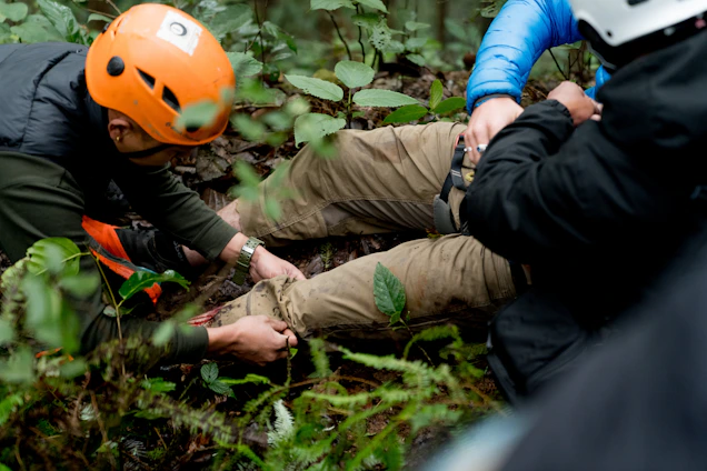 A man in an orange helmet is on the ground
