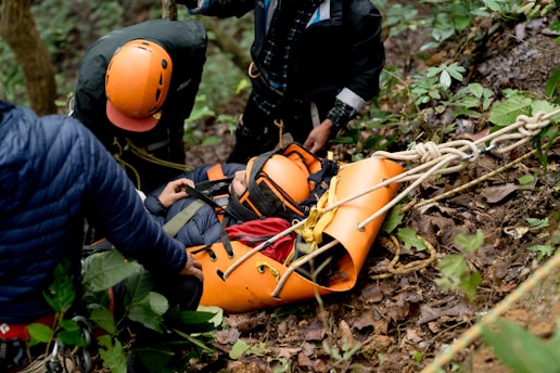 A man in an orange life jacket is being assisted by a rescue worker