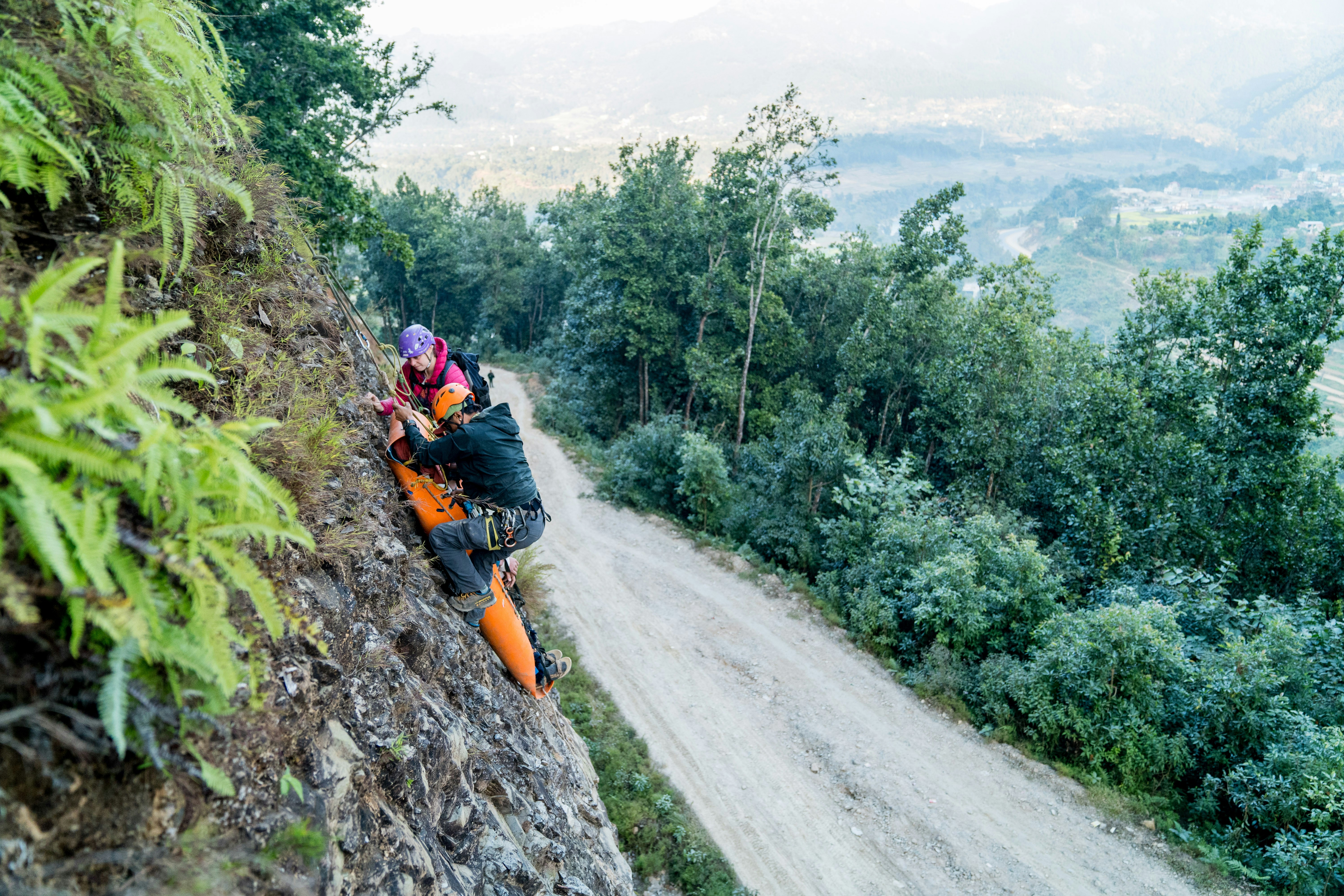 Two people climbing up a steep hill on a dirt road