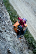A couple of people climbing up the side of a mountain