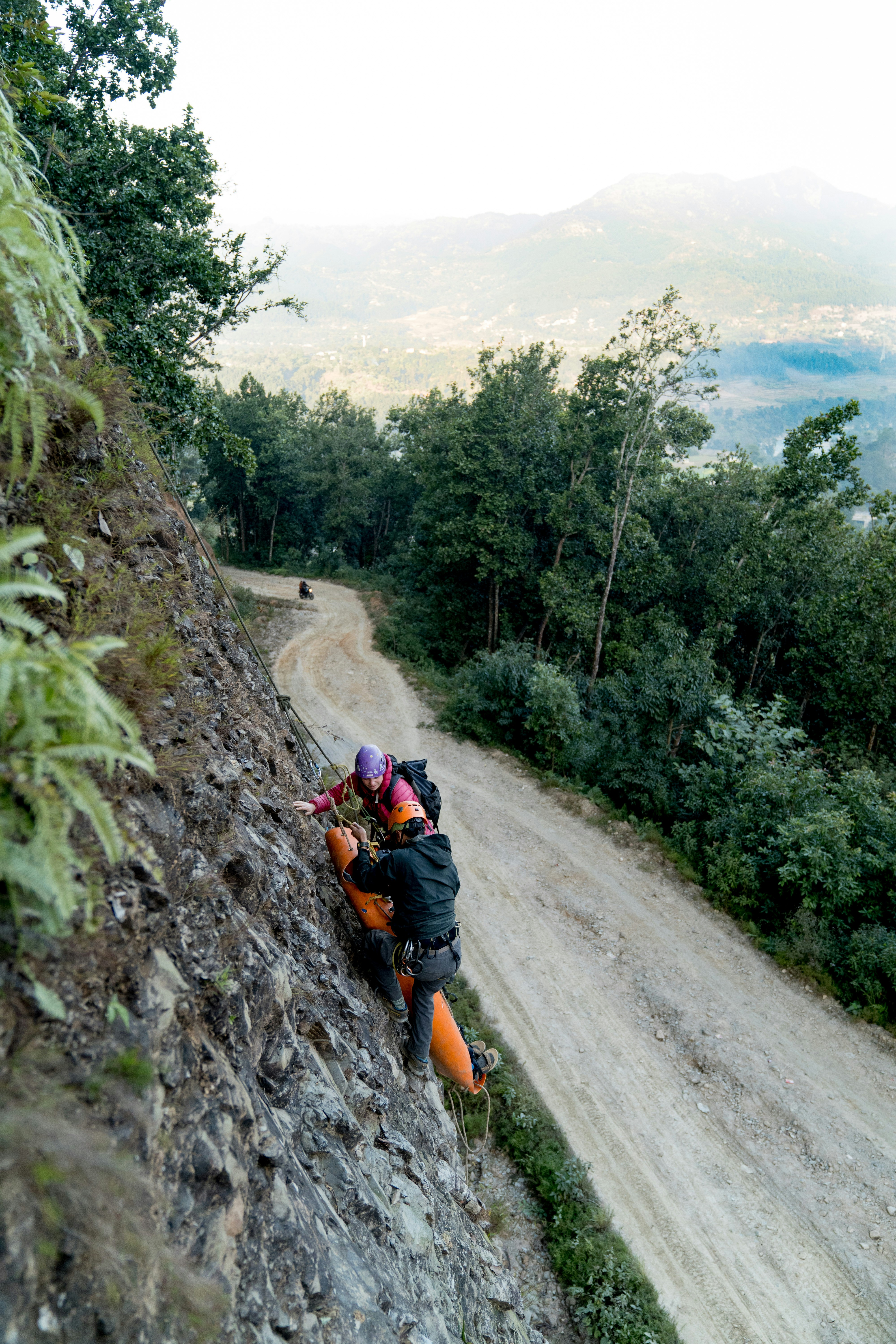 Two people climbing up a steep hill on a dirt road