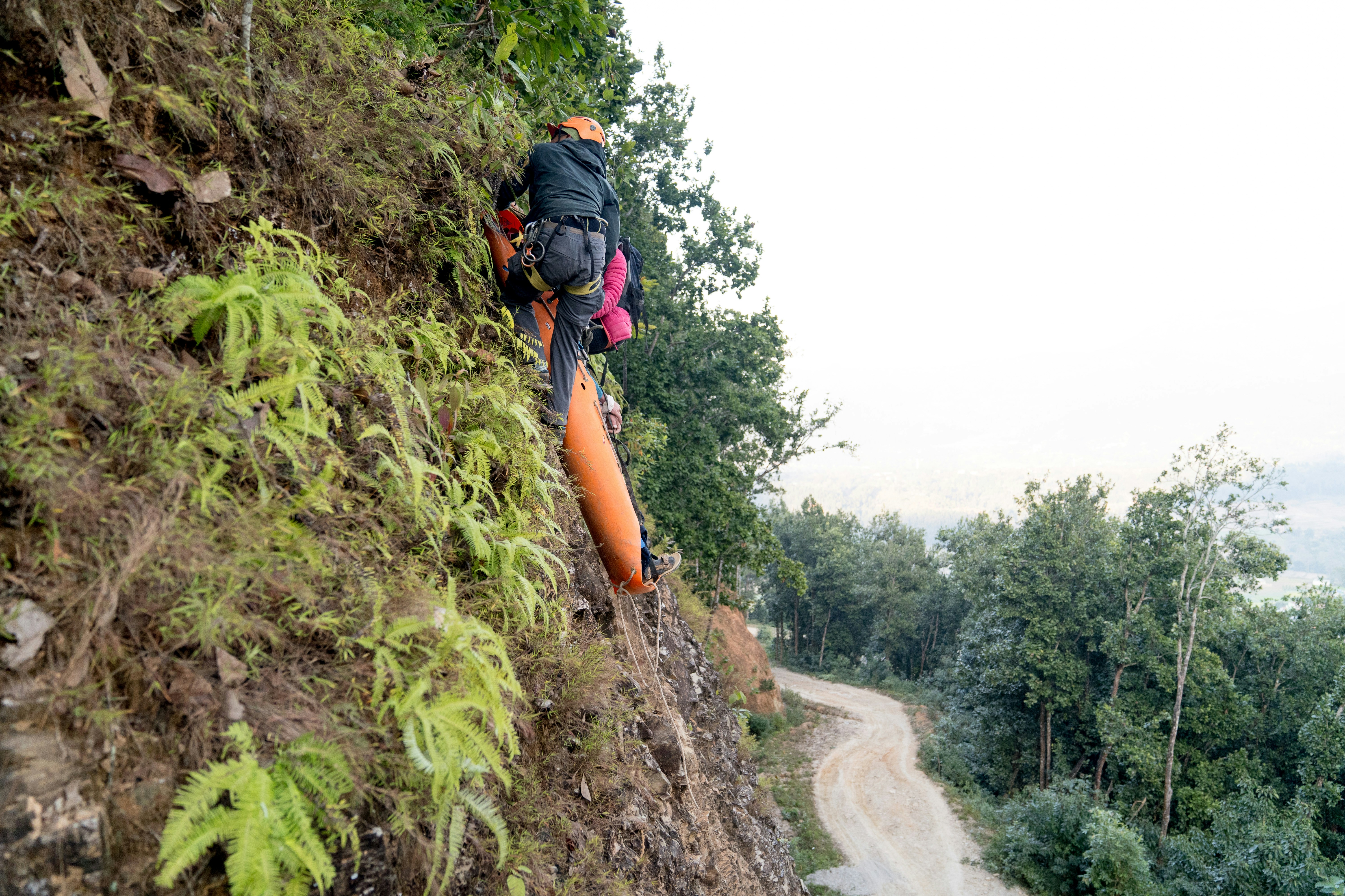 A man with a backpack climbing up a hill