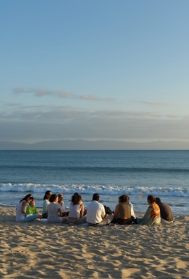 A group of people sitting on top of a sandy beach