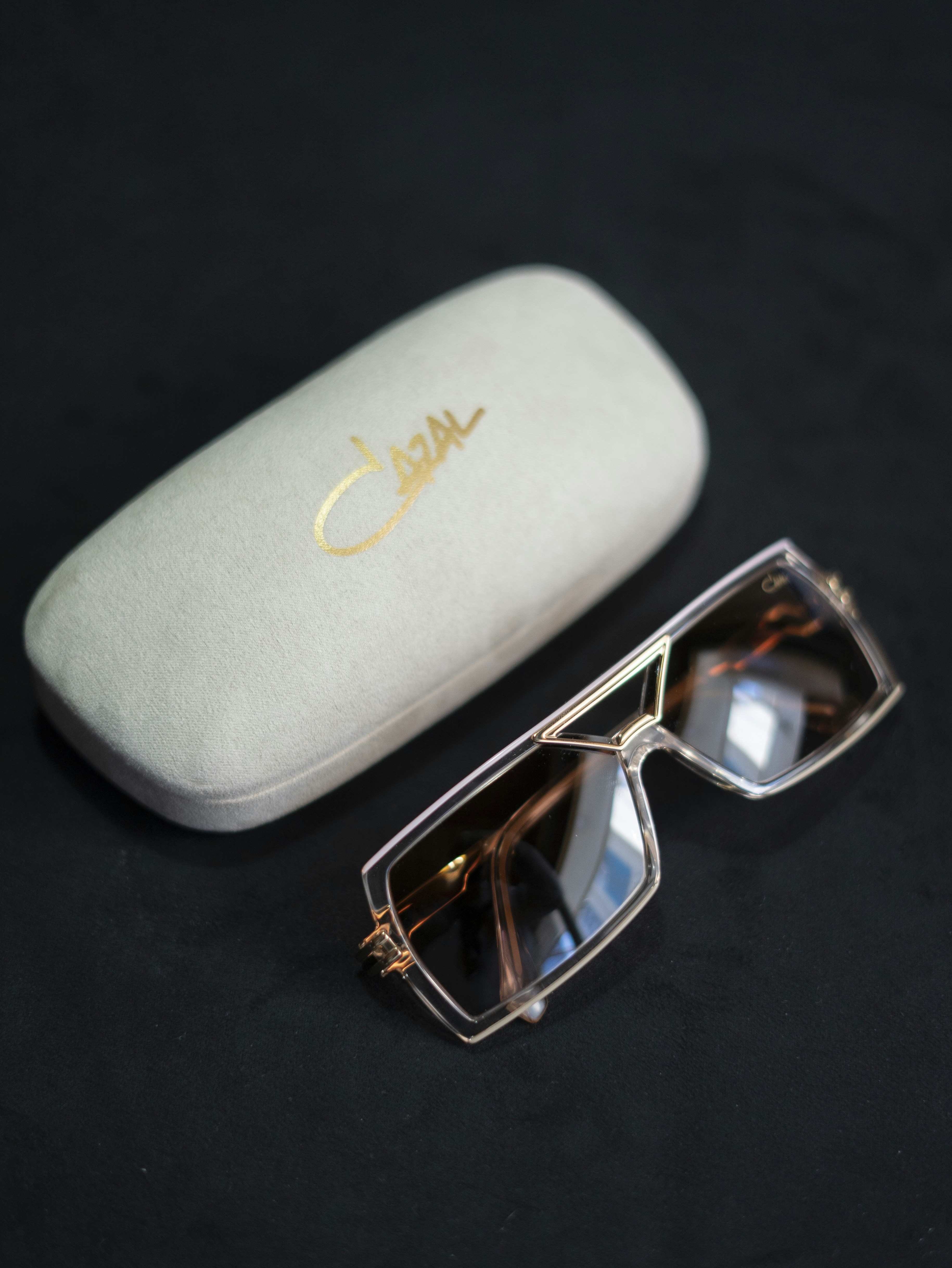 Luxury designer sunglasses with gold hardware on dark velvet surface