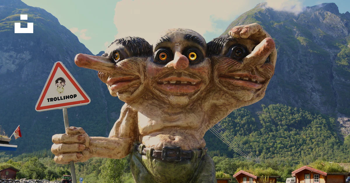 Troll Signing Off A statue of a troll holding a sign in front of a mountain photo – Free ...