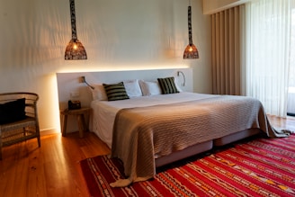 A bedroom with a large bed and a red rug