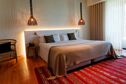 A bedroom with a large bed and a red rug