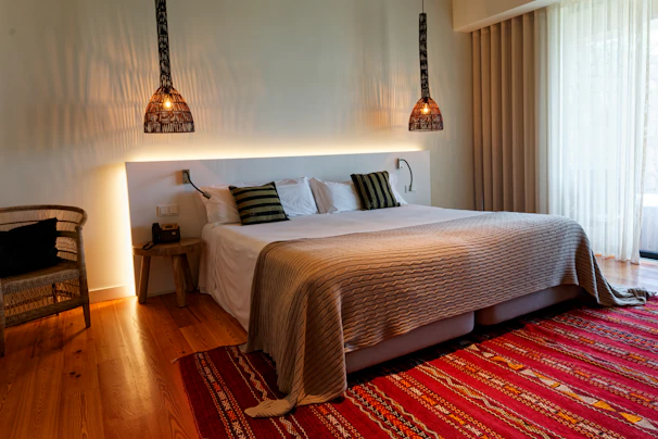 A bedroom with a large bed and a red rug