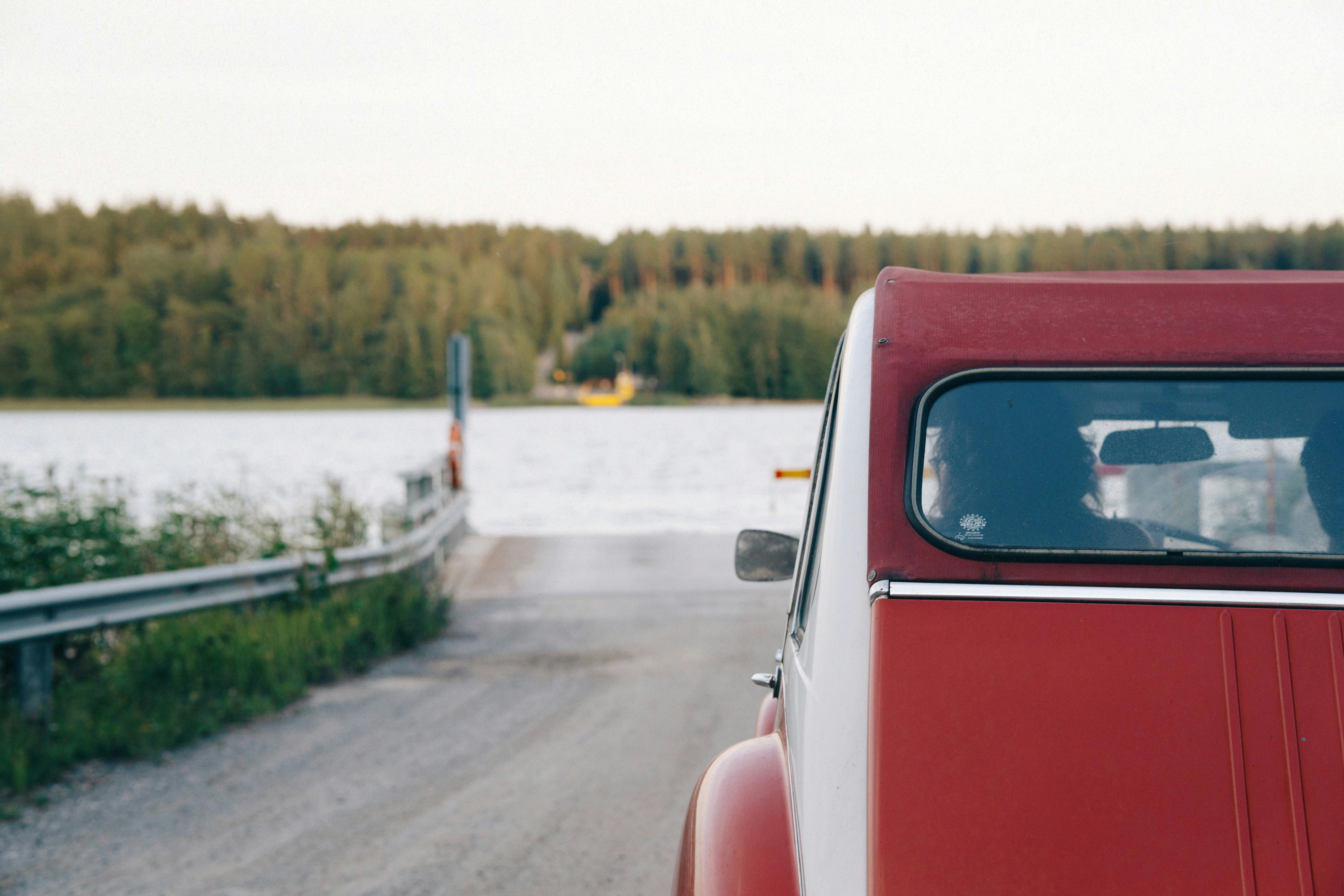 A red truck parked on the side of a road, A classic Citroën car parked in line, waiting for a ferry.