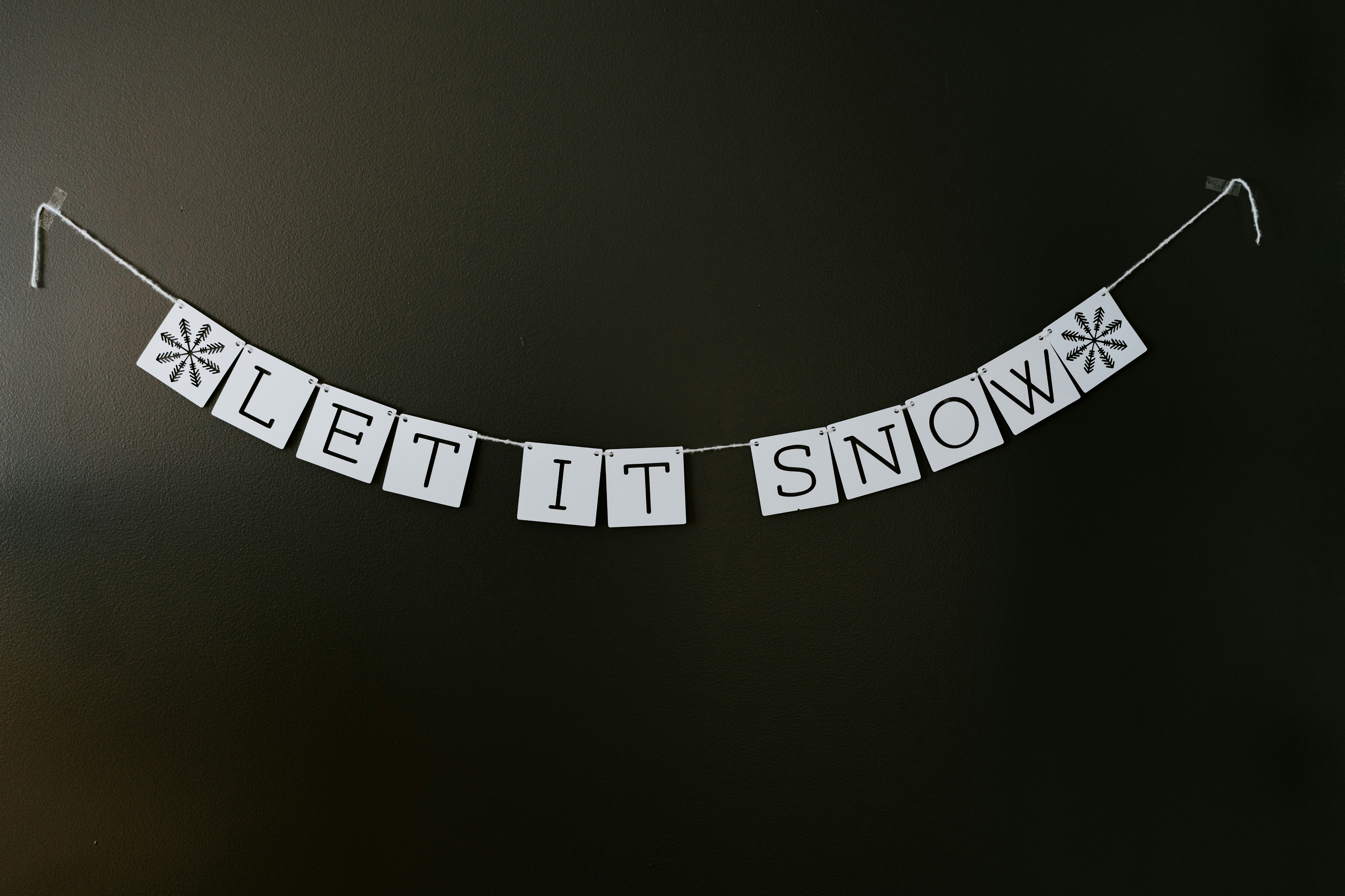 A black and white photo of a sign that says let it snow