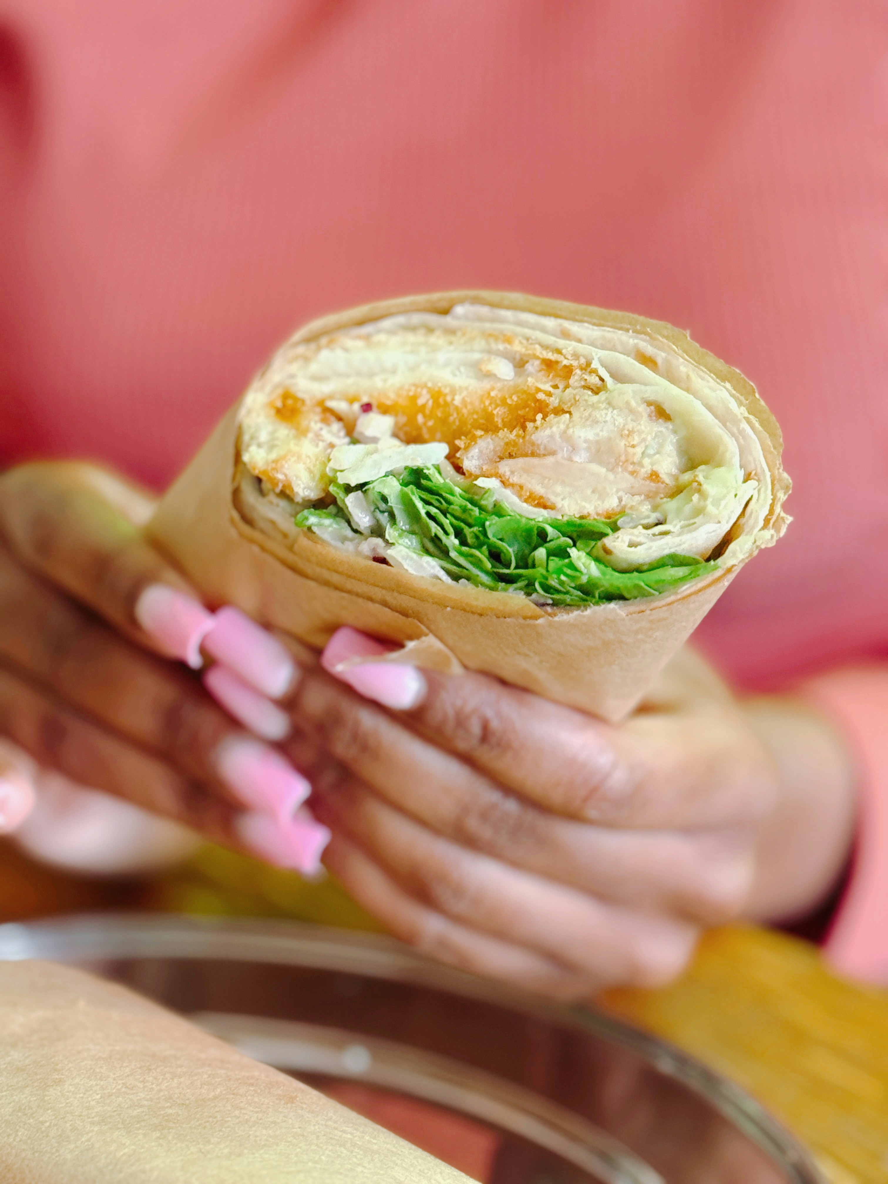Sliced chicken wrap showing layers of grilled chicken, crisp lettuce, and golden sauce, dramatic dark background
