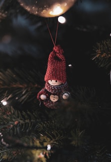 A teddy bear ornament hanging from a christmas tree
