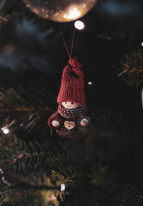 A teddy bear ornament hanging from a christmas tree