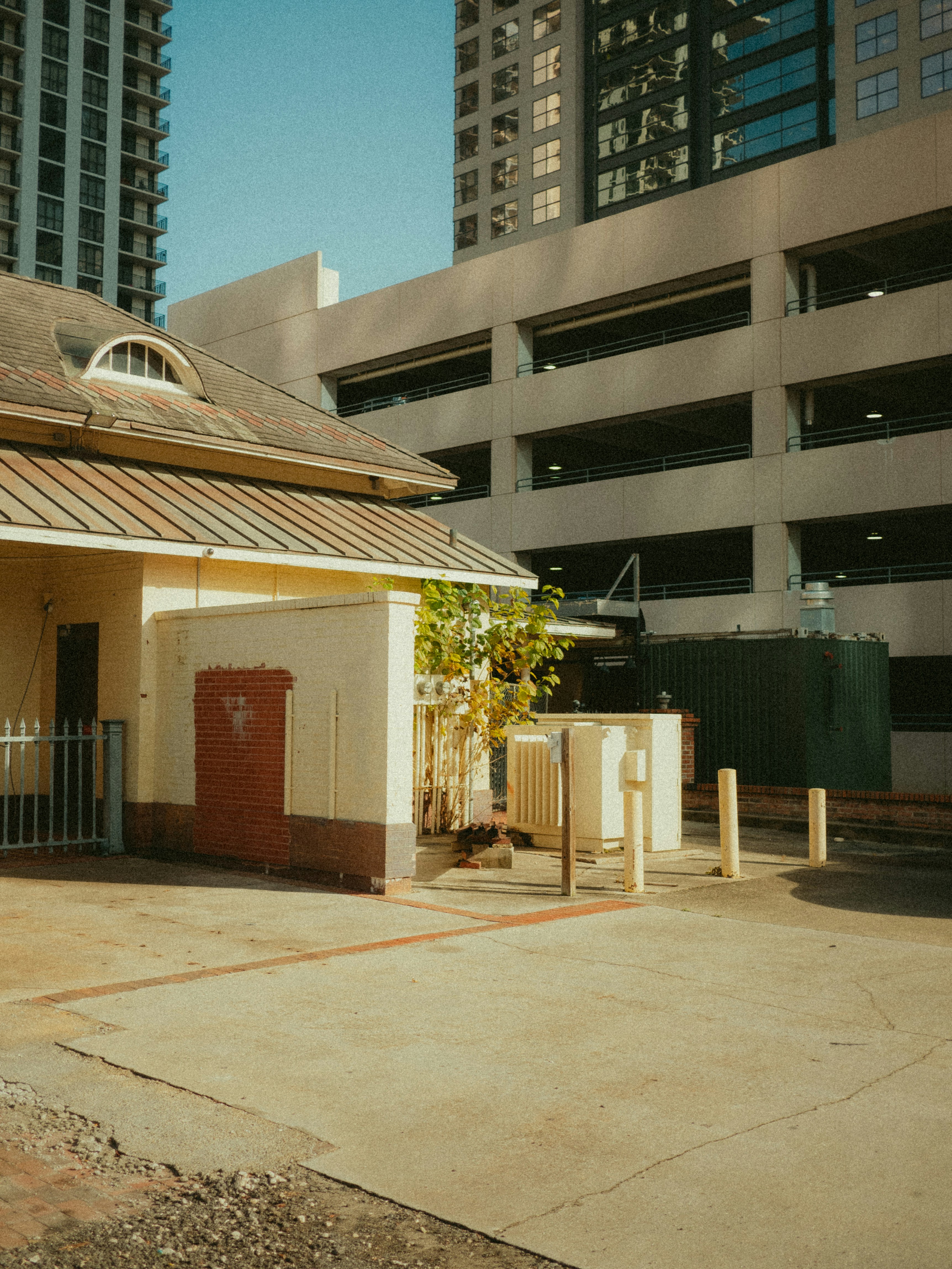 A small building with a metal roof in front of a tall building