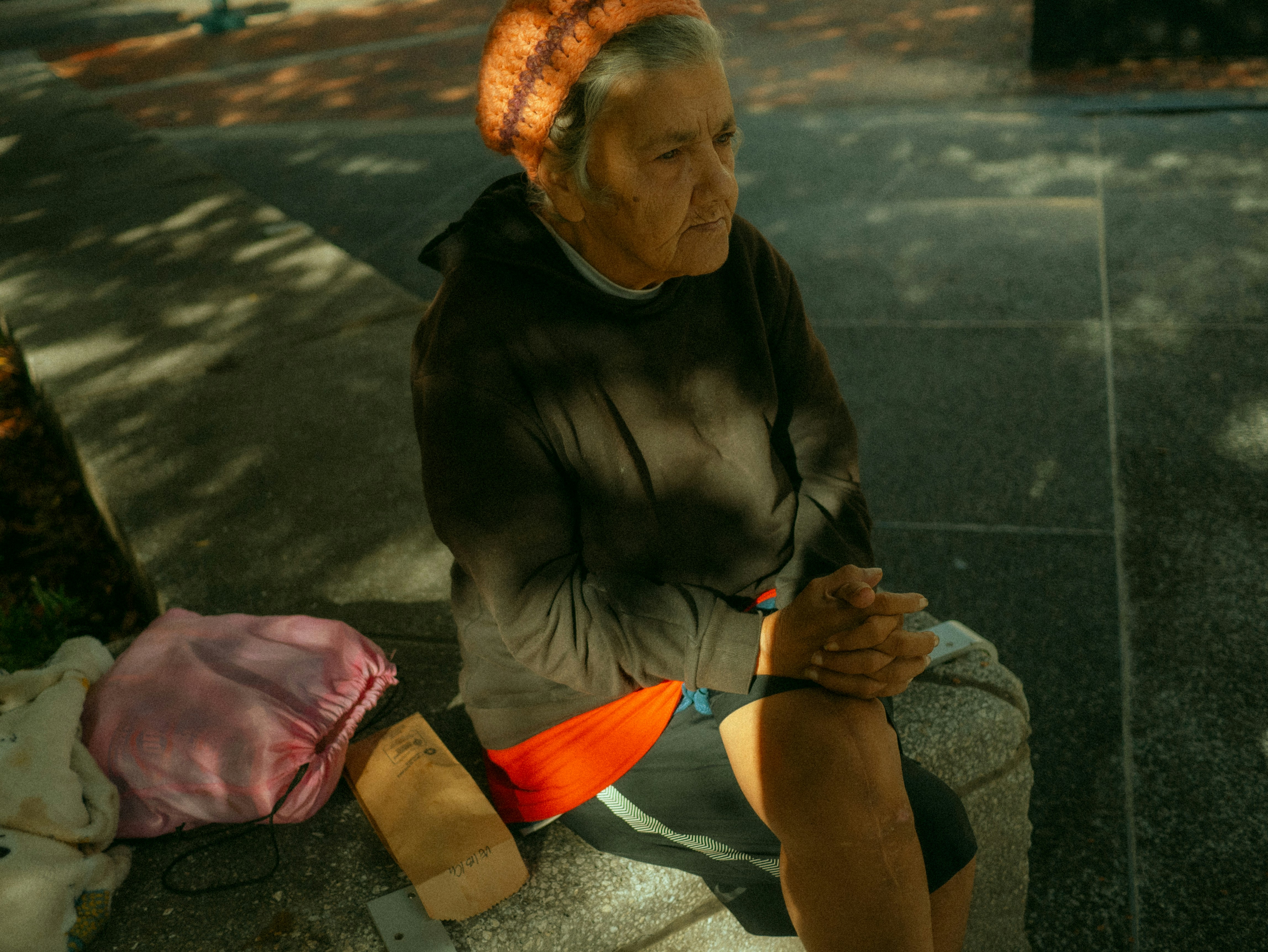 A woman sitting on a curb with her hand on her knee